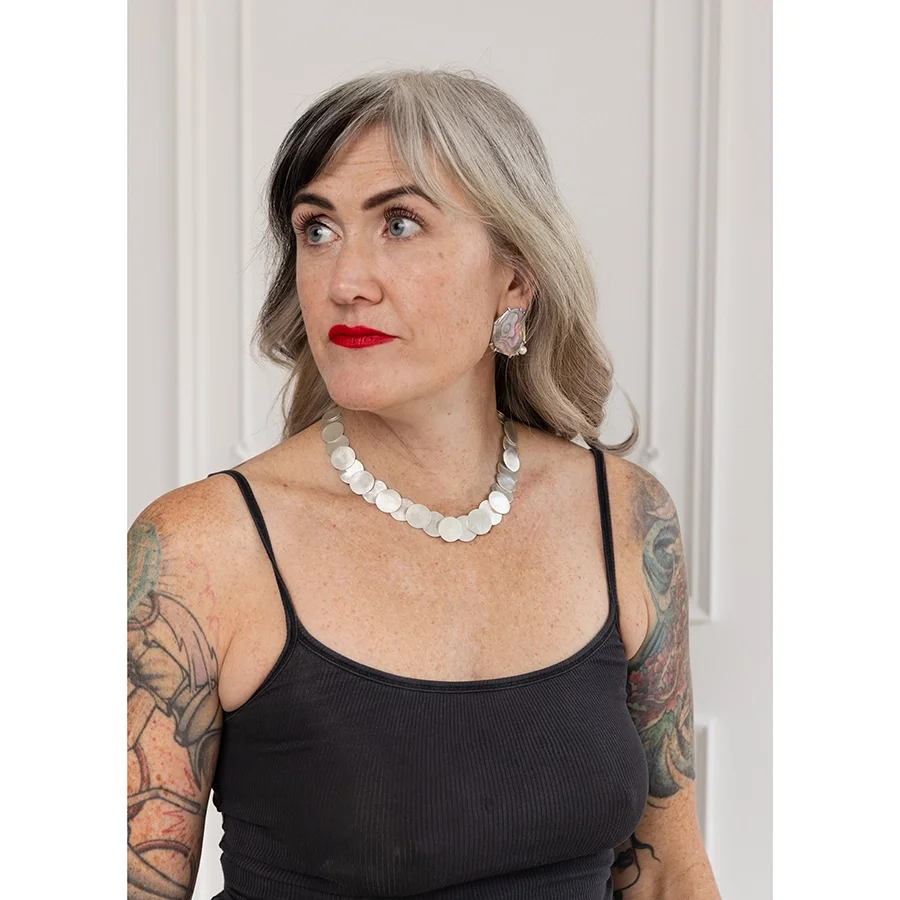 woman with blond hair black tank top and red lips wearing shiny sterling silver round link necklace and pink and purple shell earrings