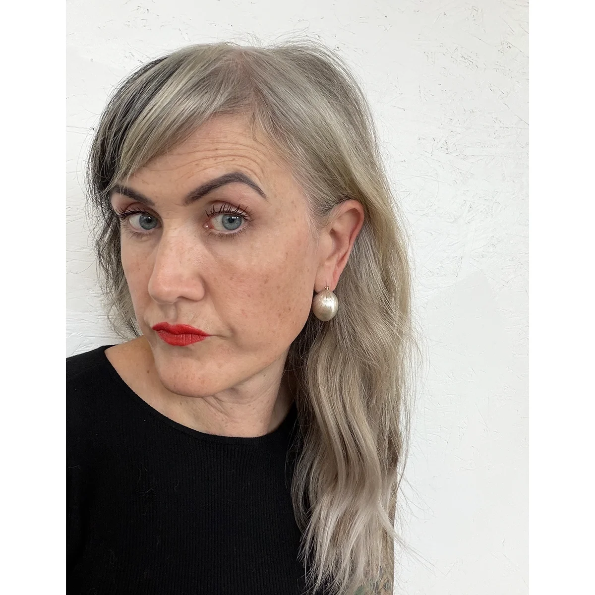 woman with blue eyes black top wavy blond hair and red lips wearing large brushed sterling silver ball earrings with engraved lines