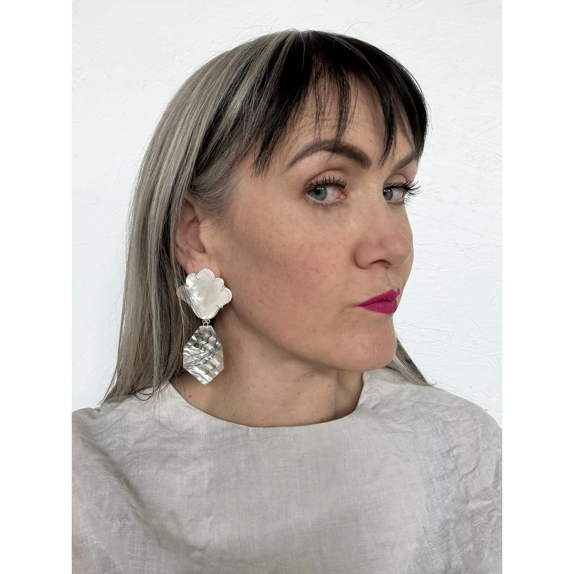 woman with blonde hair and pink lipstick wearing large flashy pearl earrings
