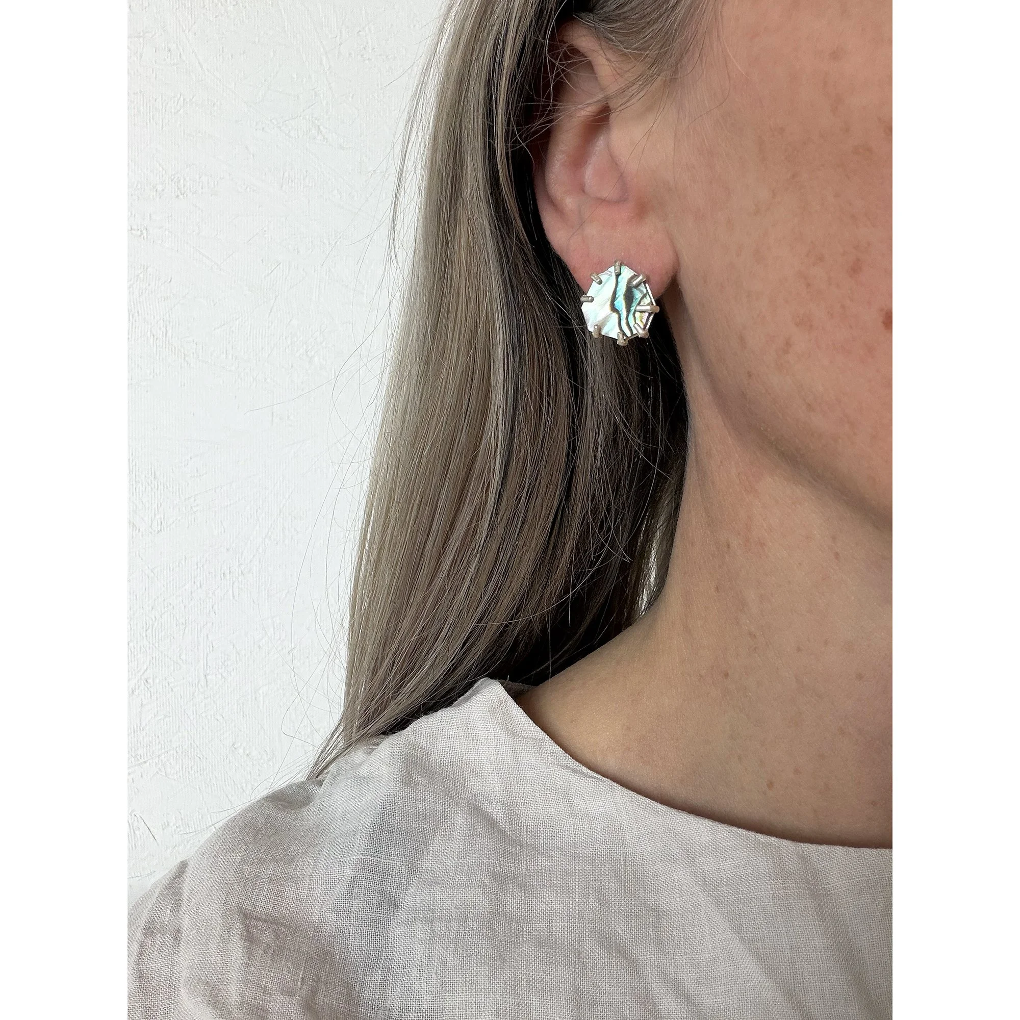 small green abalone post earrings on blonde woman with white shirt