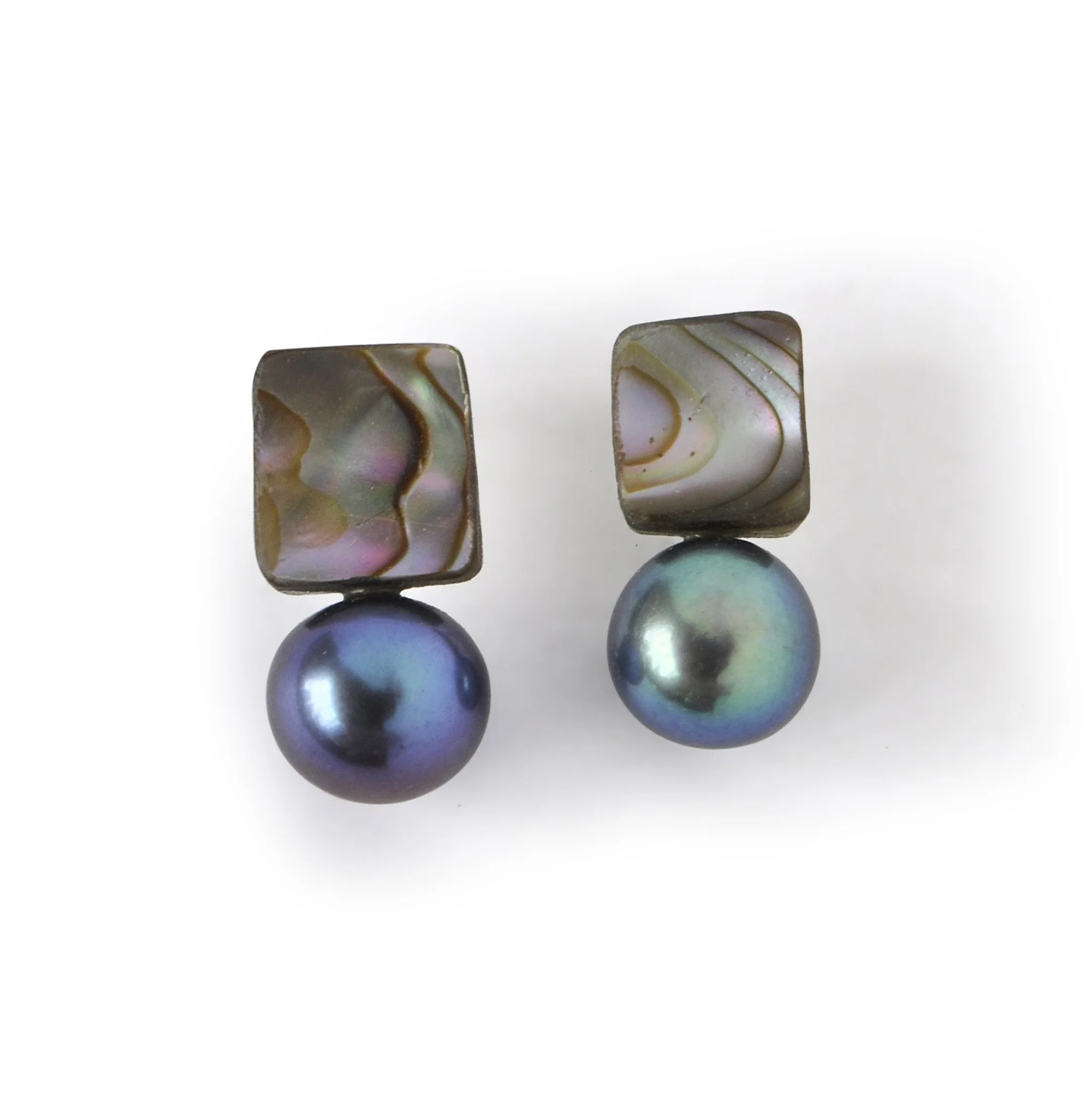 small square red abalone shell piece with purple blue green and pink flashes next to a dark blue green pearl