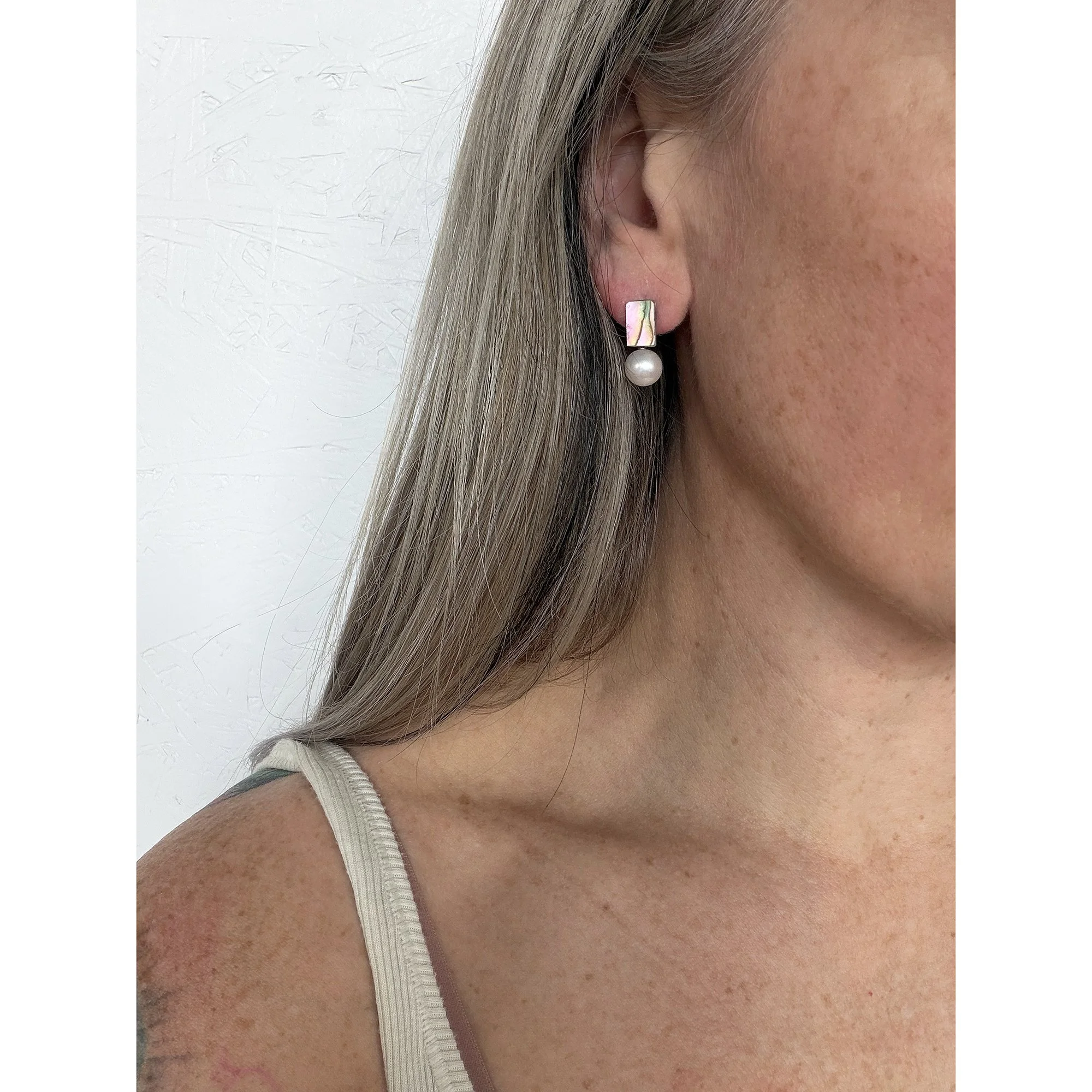 side view close up of woman with blonde hair and freckles wearing small pearl white round freshwater pearl and mother of pearl chunk earrings