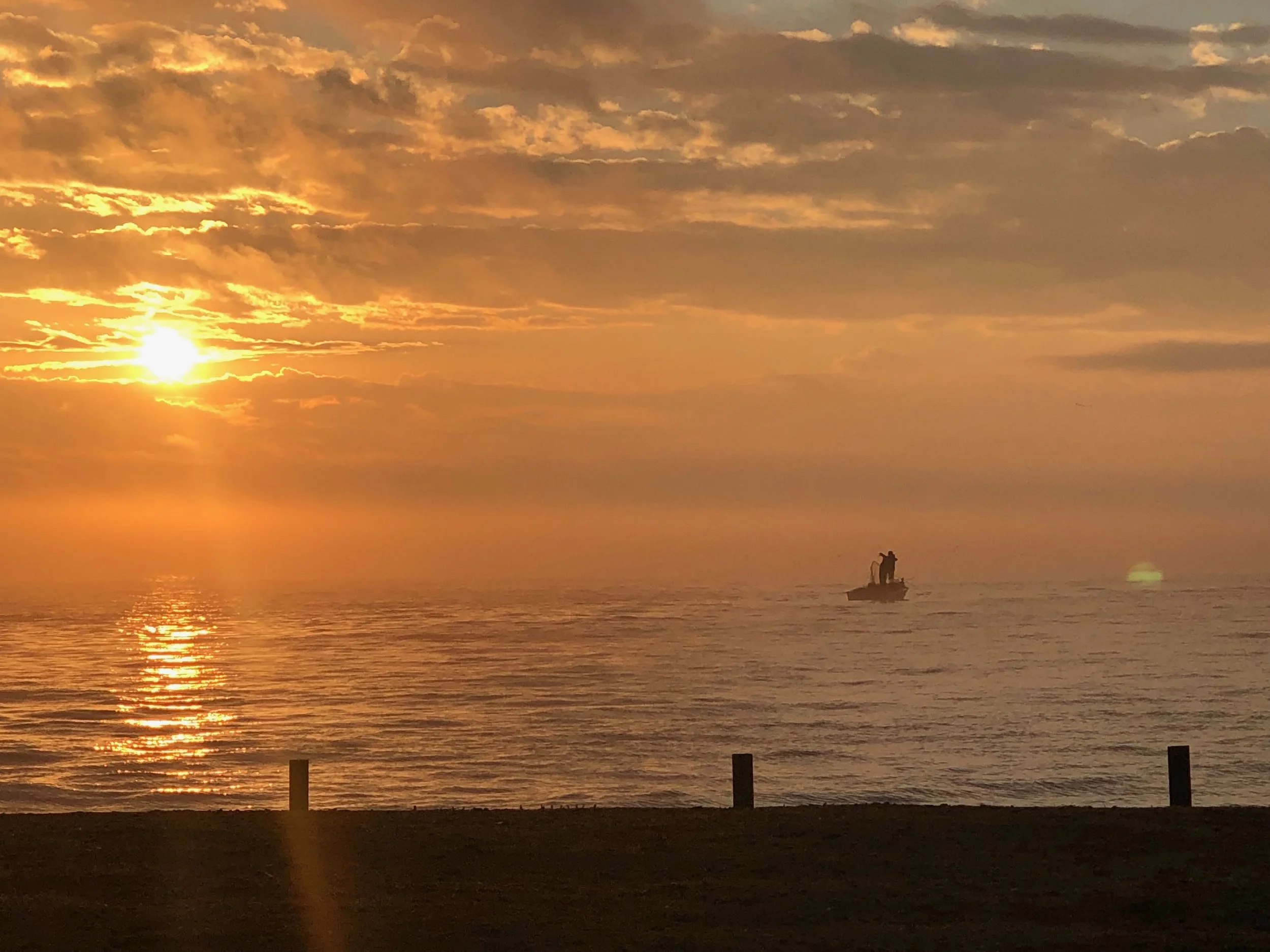 Two figures against the horizon — carried by water, lit by morning fire.