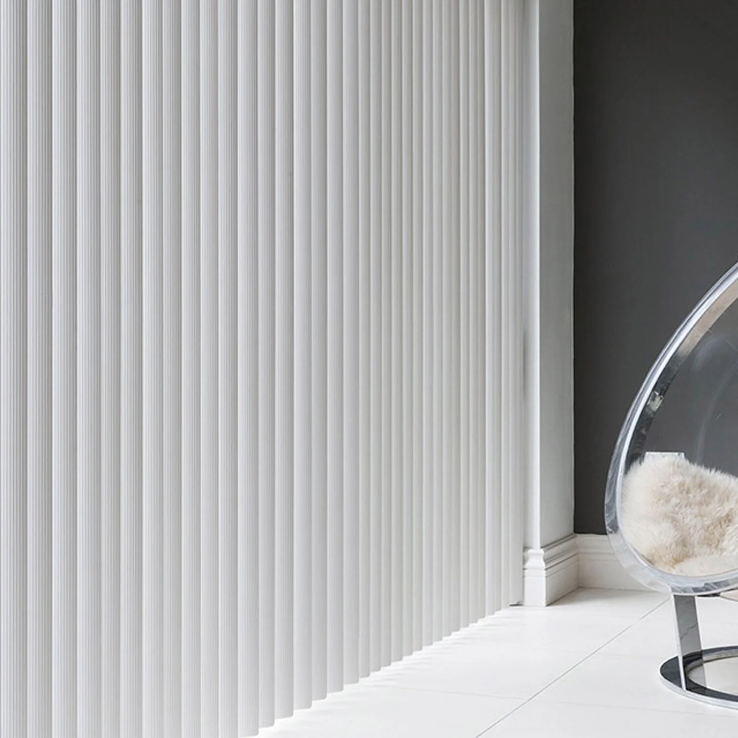 Modern interior with vertical white panel wall and a clear acrylic chair with a furry white cushion.