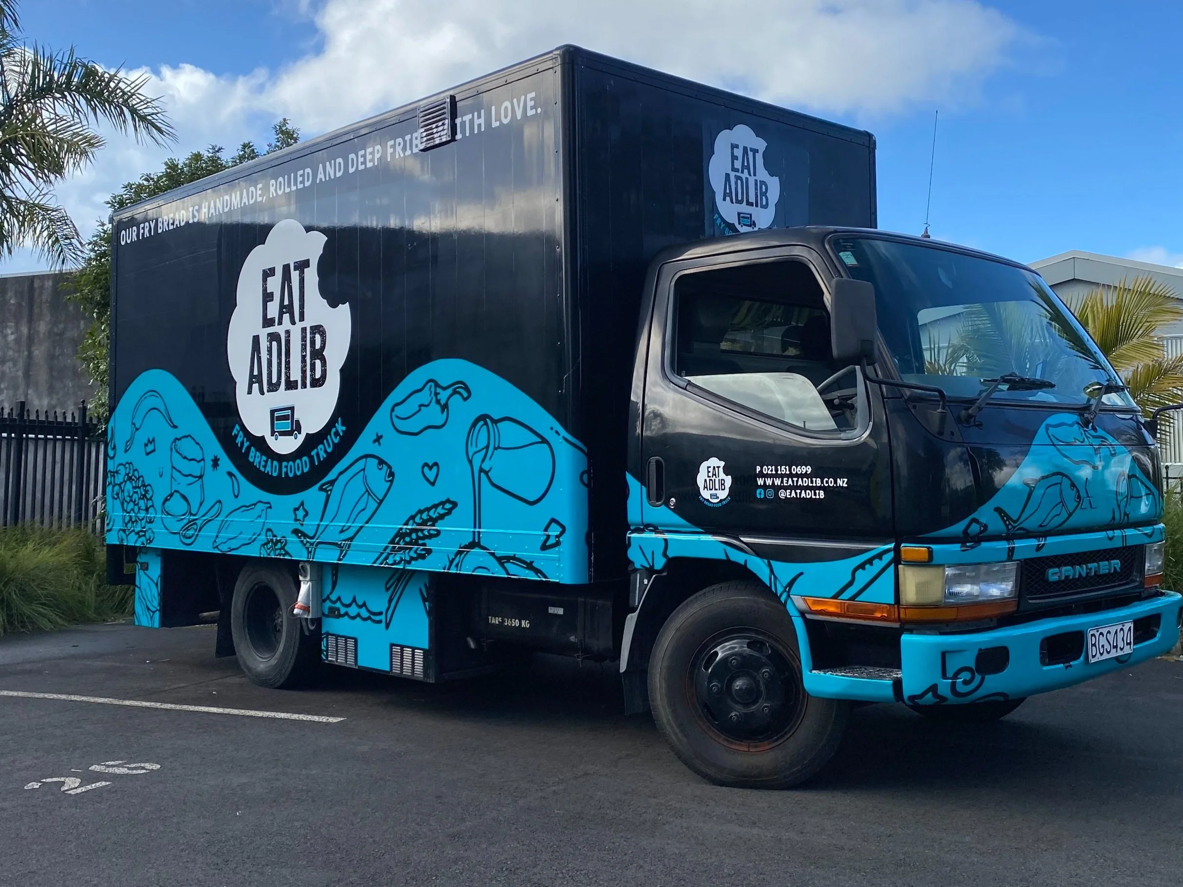 Food truck with "Eat Adlib" branding, featuring illustrations and contact information.