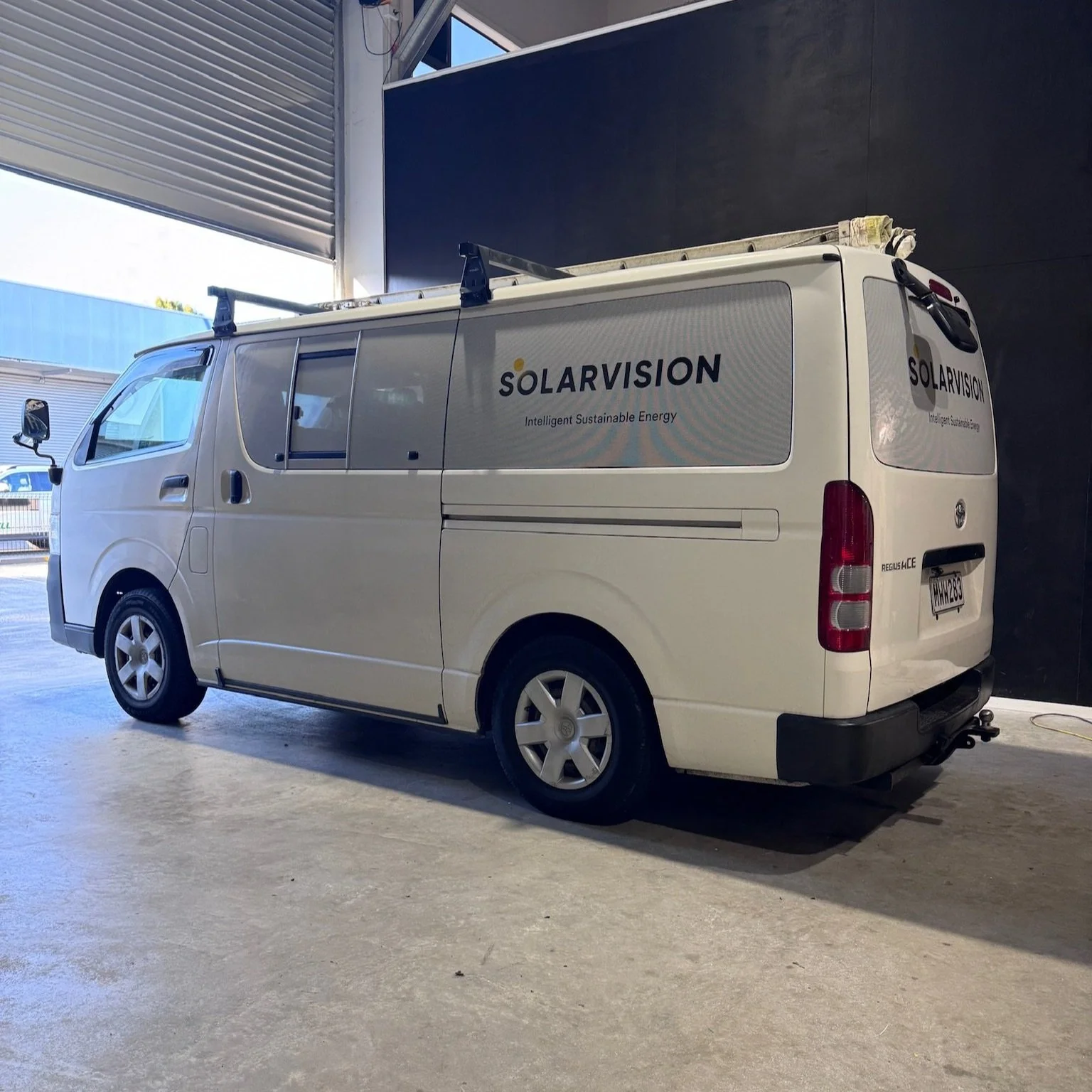 White van with "Solar Vision" logo parked indoors