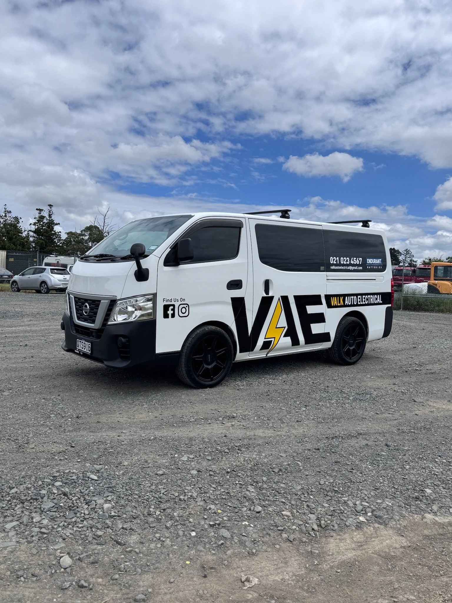 White Nissan van with "VAE" and "Walk Auto Electrical" branding, parked on gravel, overcast sky.