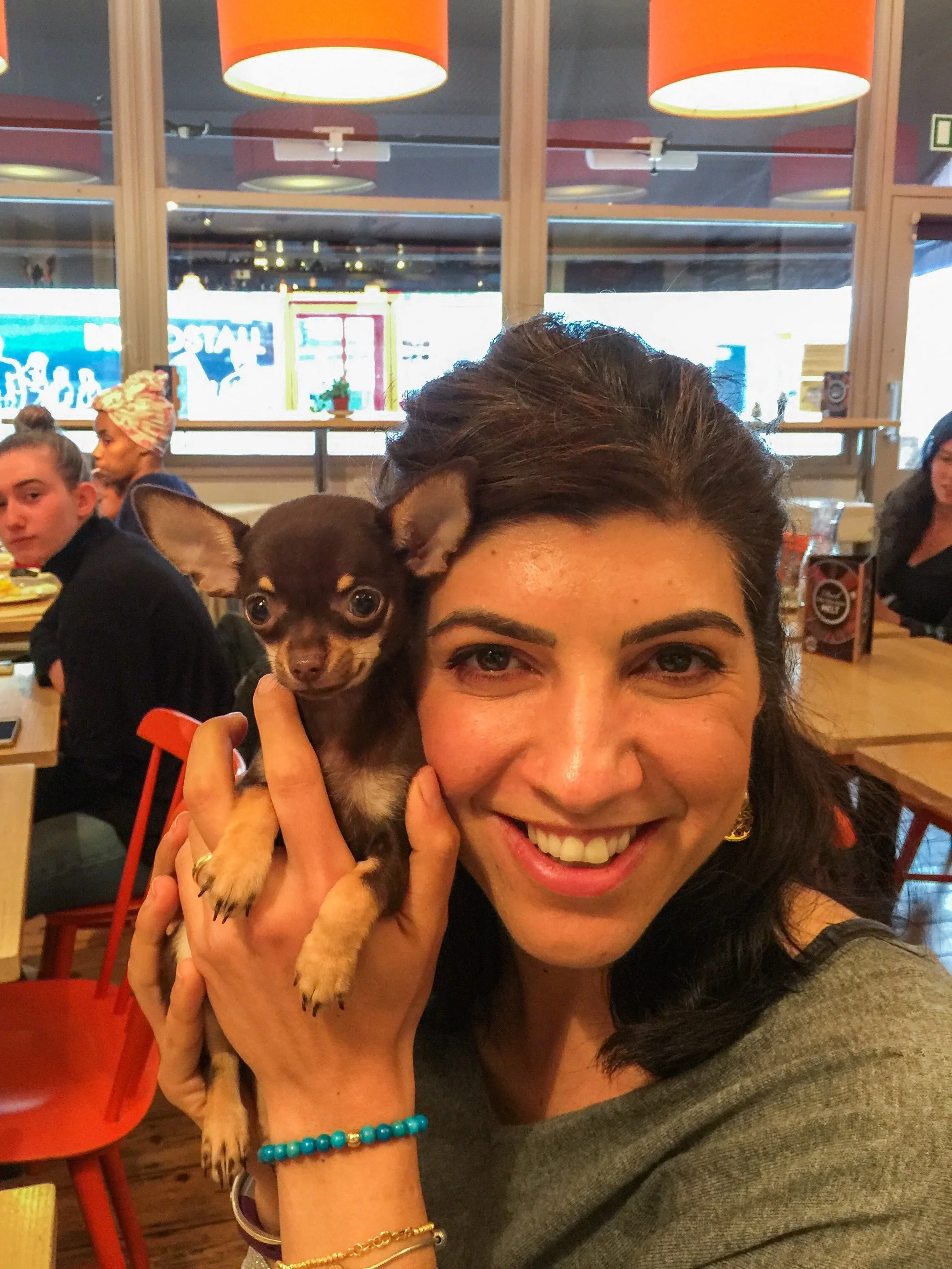 Melda, one of the founders, smiling and holding a small dog, Peanut, at Cafe Tamra, a healthy brunch café.