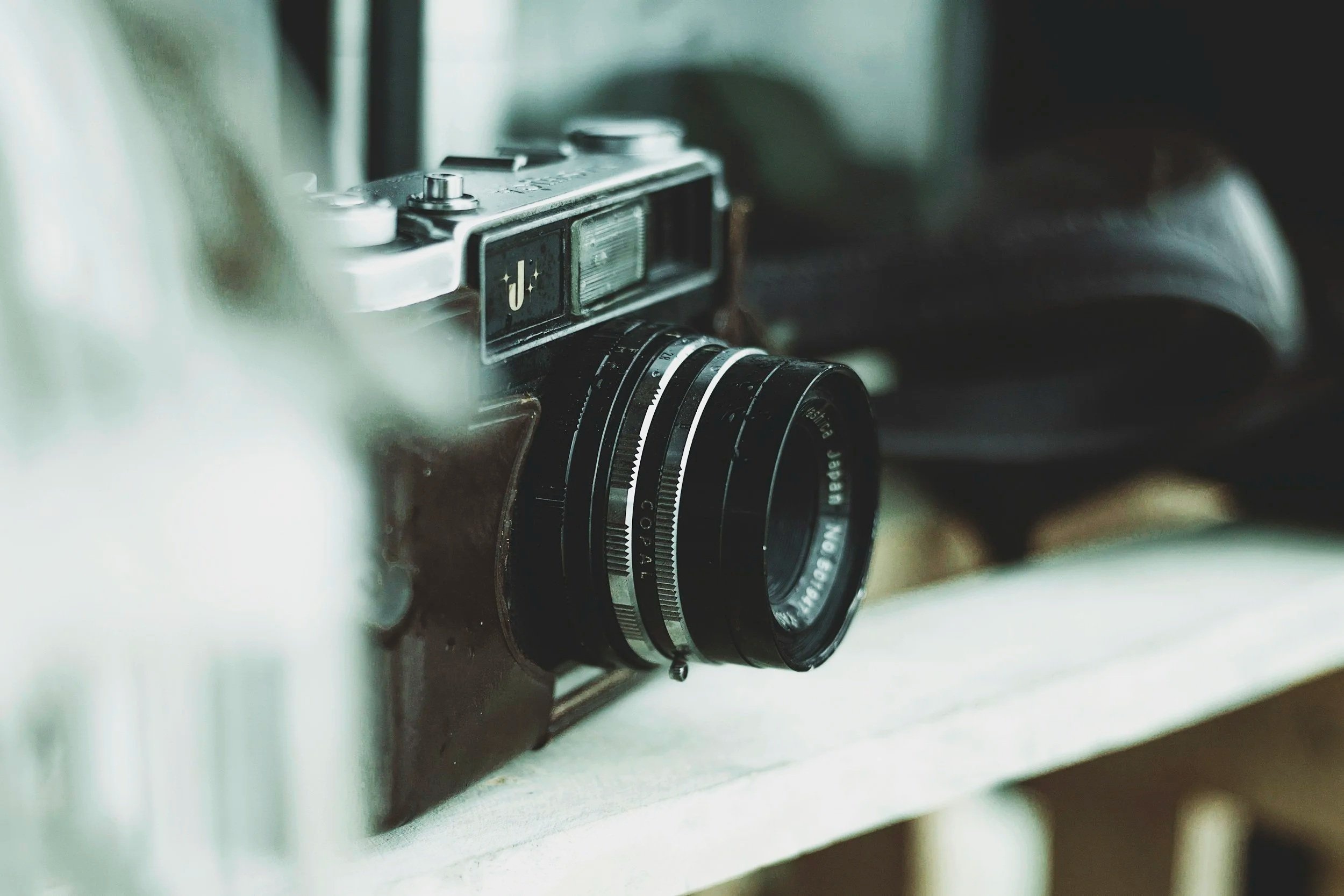 Een vintage camera ligt op een tafel, de foto is genomen in een close-up en heeft een vage achtergrond.