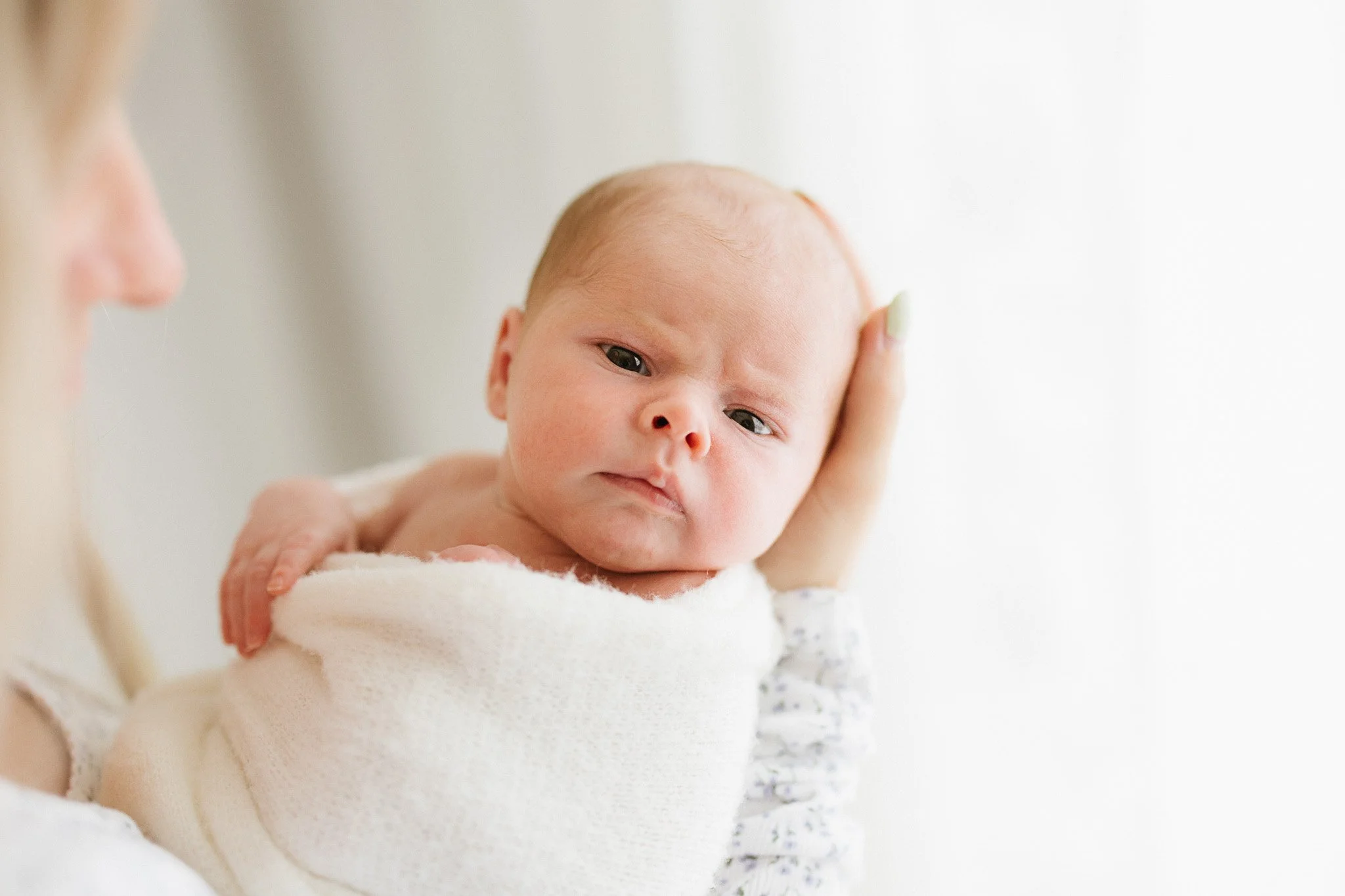 Baby gazes at the camera during an intimate and soft newborn photoshoot Cornwall