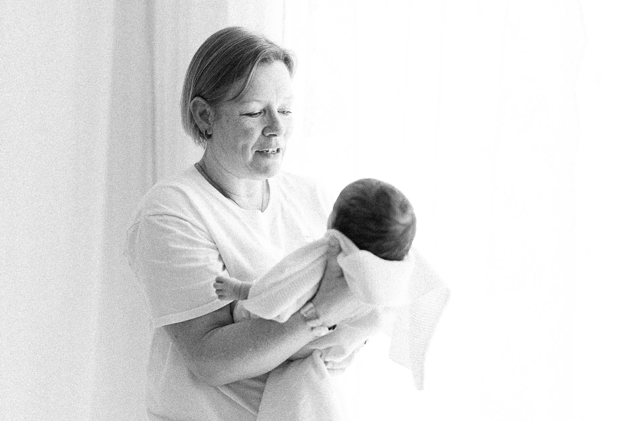 Photographer in Cornwall holding a newborn baby during newborn photoshoot