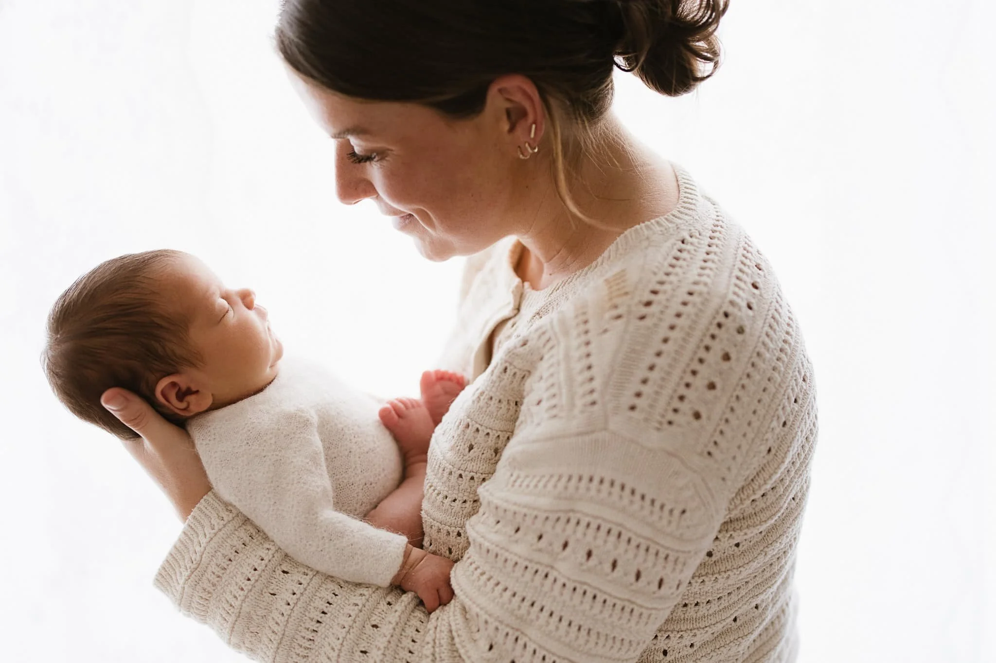 Mother gazing at newborn baby during newborn photoshoot in Cornwall