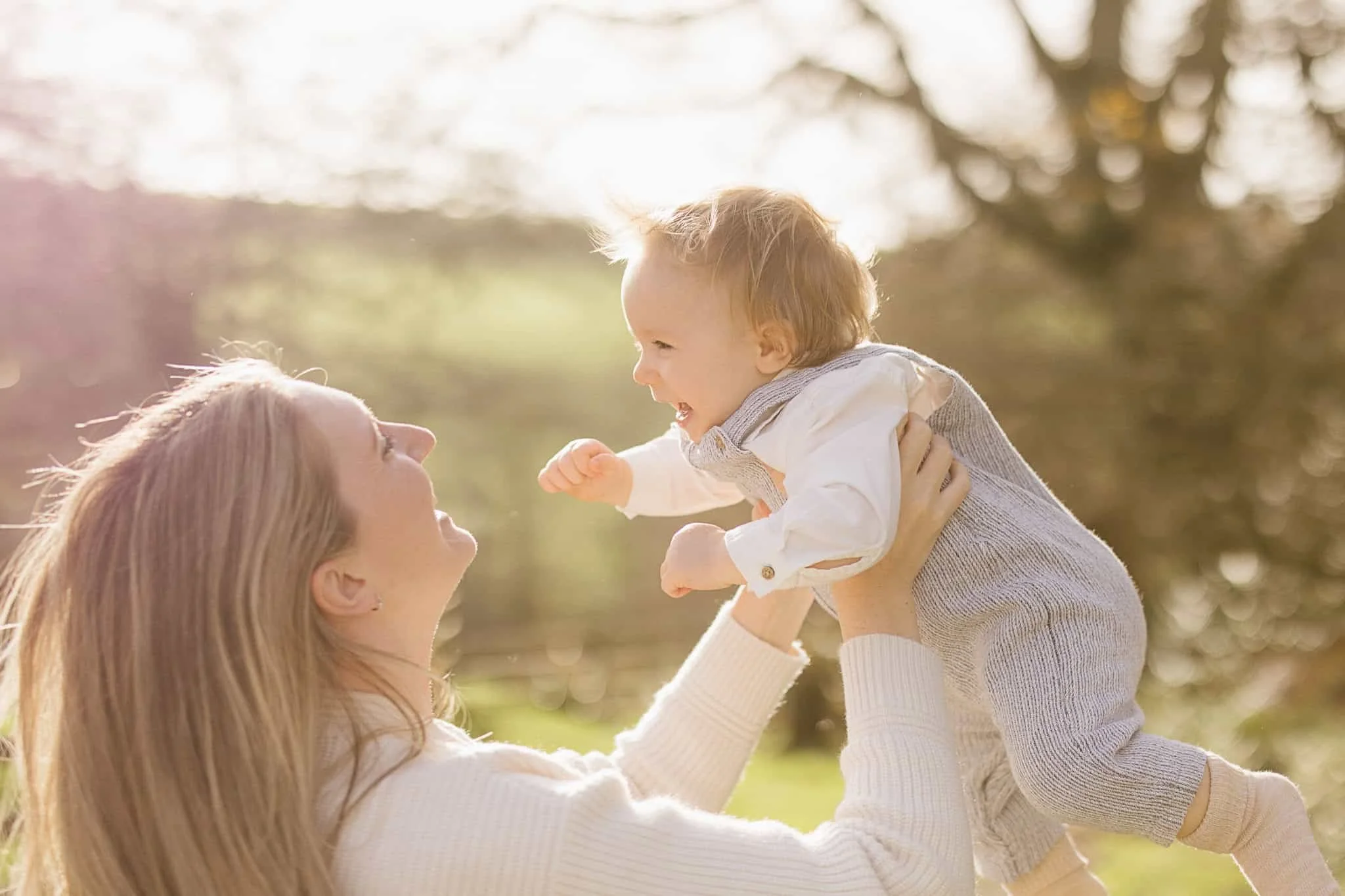 Mother playfully lifts one year old baby boy during first birthday milestone photoshoot in Cornwall