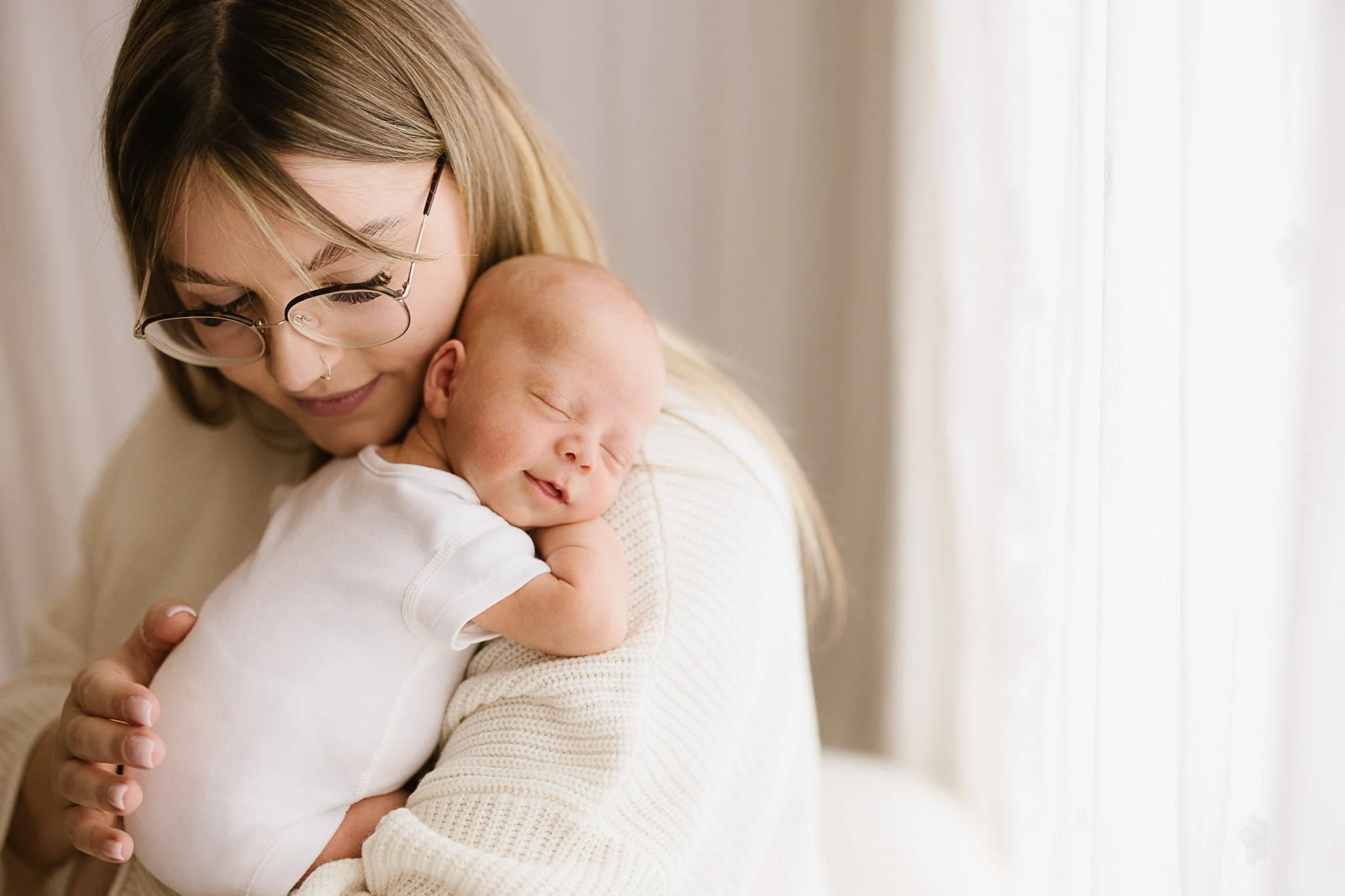 Mother wearing cream jumper and newborn cuddling during newborn photoshoot in Cornwall
