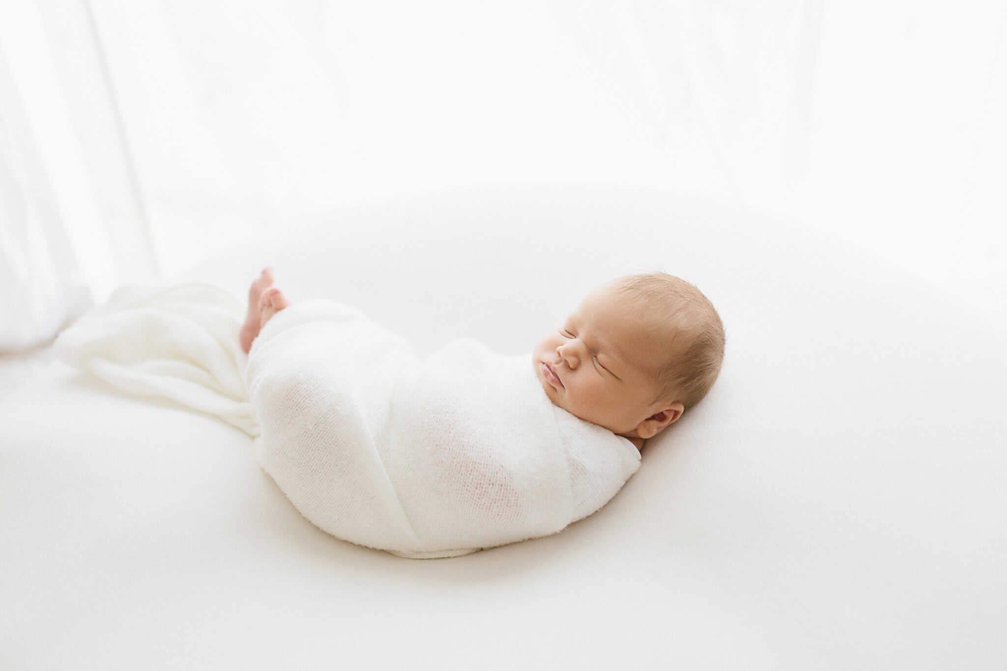 Swaddled newborn in white