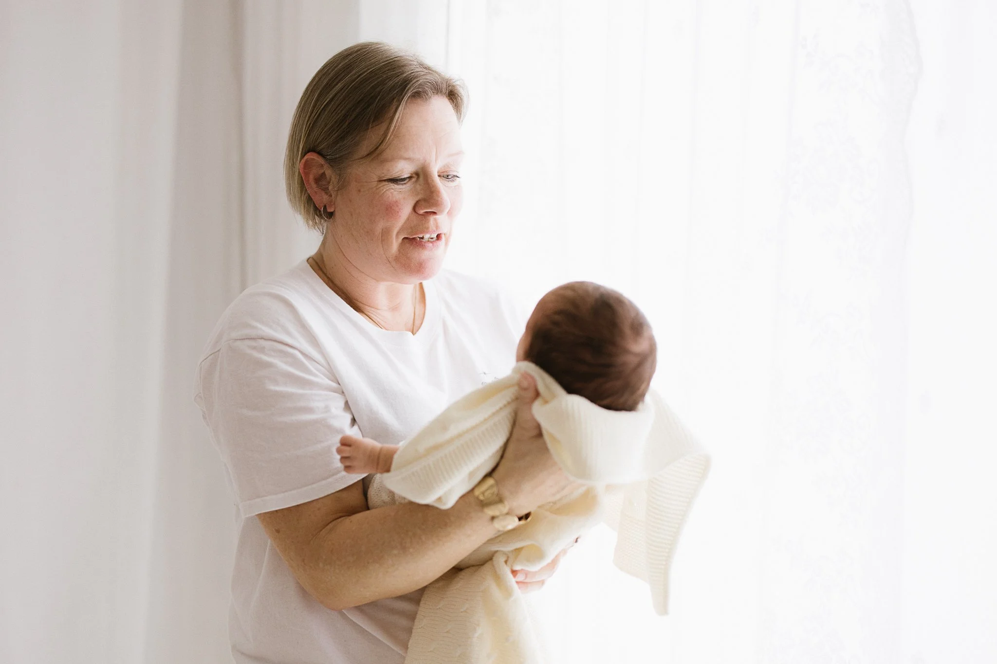 Michelle, newborn photographer in Cornwall, holding a baby in her Grampound studio