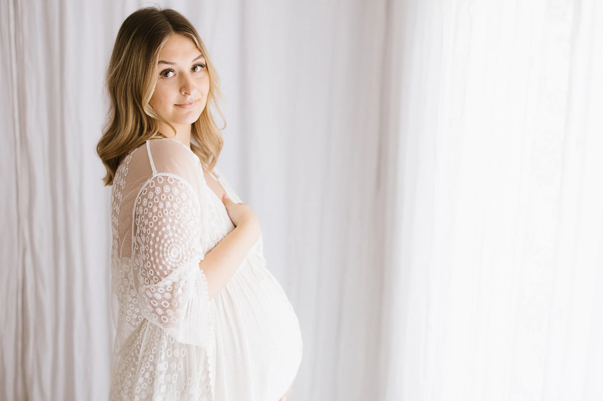 Maternity portrait in white lace dress, natural light studio Cornwall