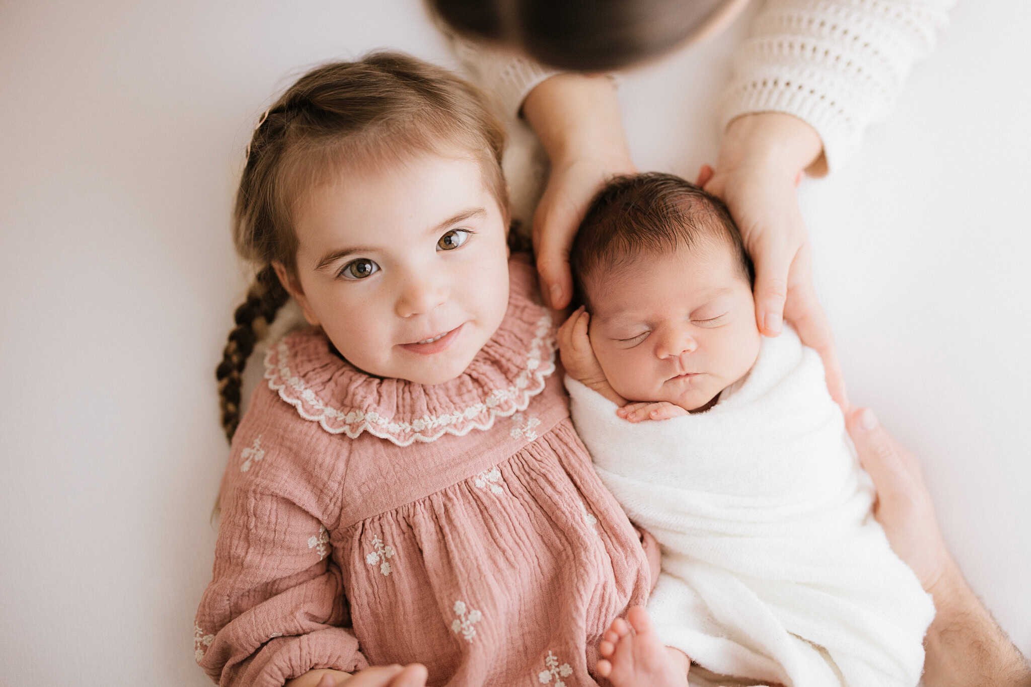 Toddler in pink dress with newborn baby sister during natural newborn photoshoot Cornwall