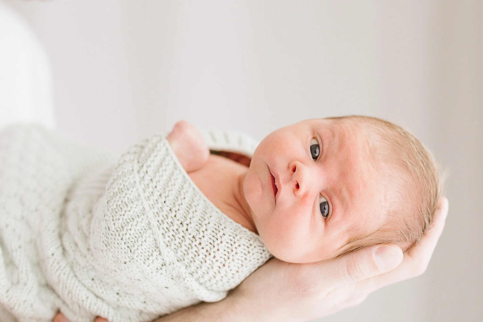 Baby swaddled in sentimental green blanket during natural newborn photoshoot in Cornwall