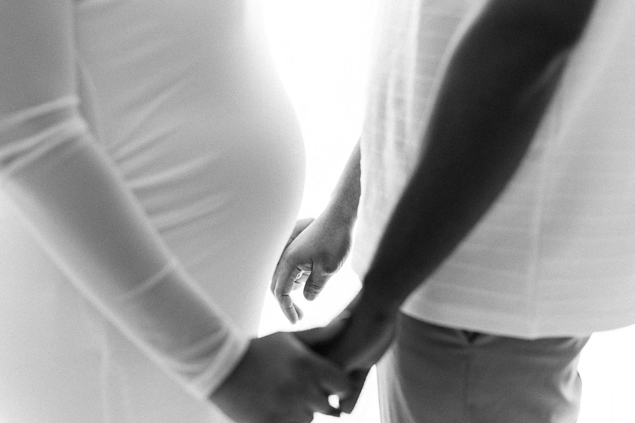 couple holding hands and baby bump black and white