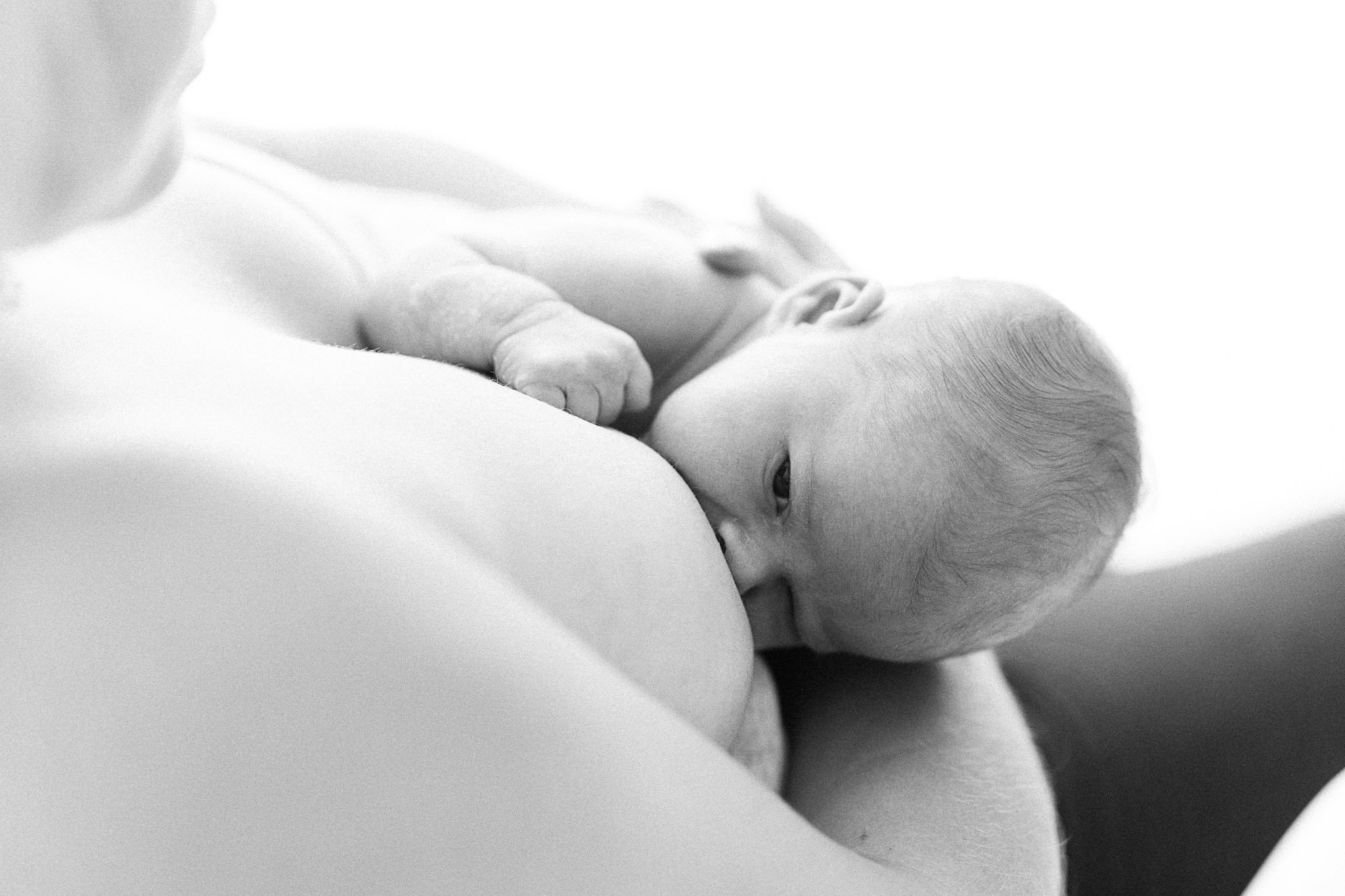 Mum breastfeeding newborn baby during relaxed newborn photography session in Cornwall