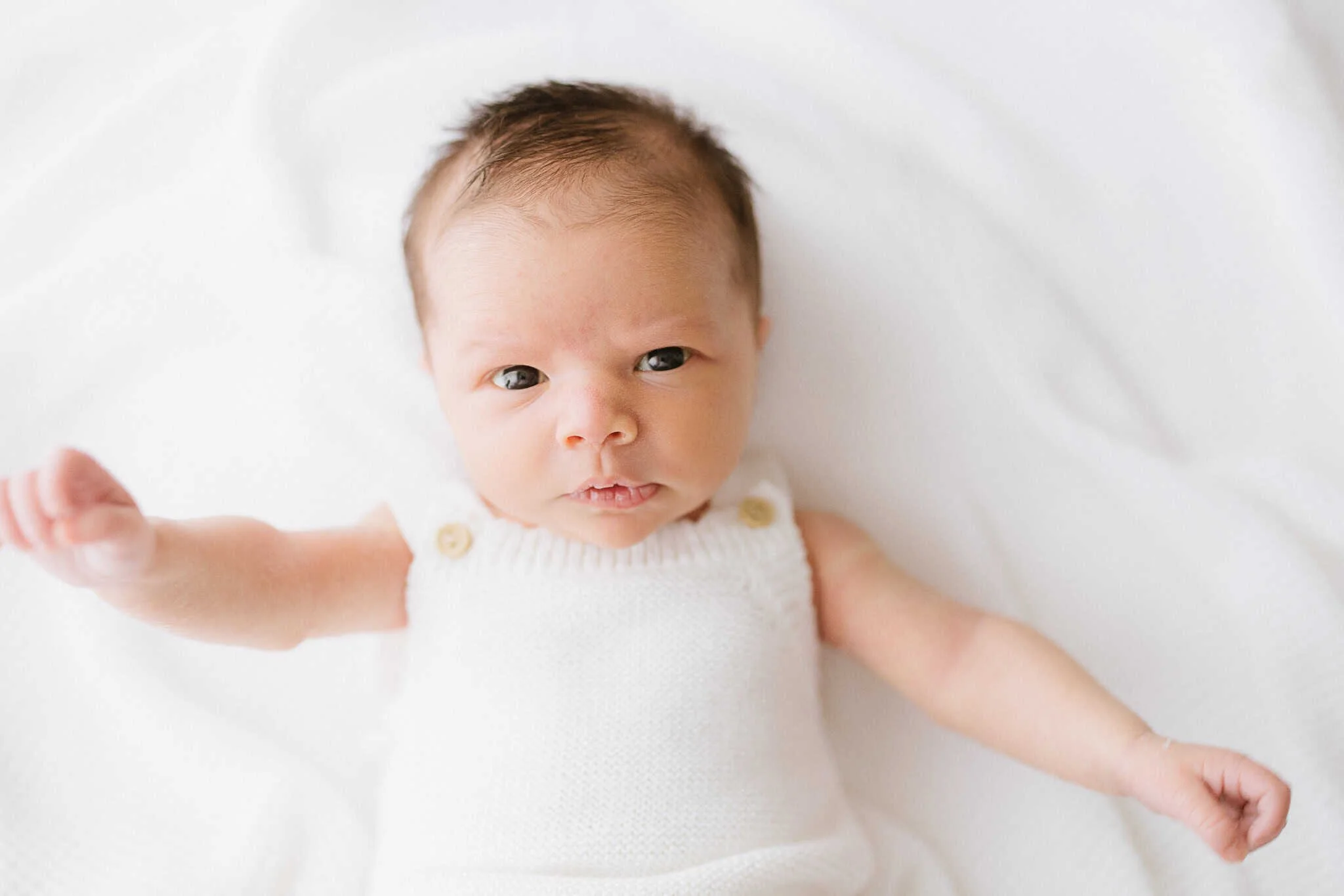 Older newborn session for 3 week old baby, eye contact with camera during newborn photograph Cornwall