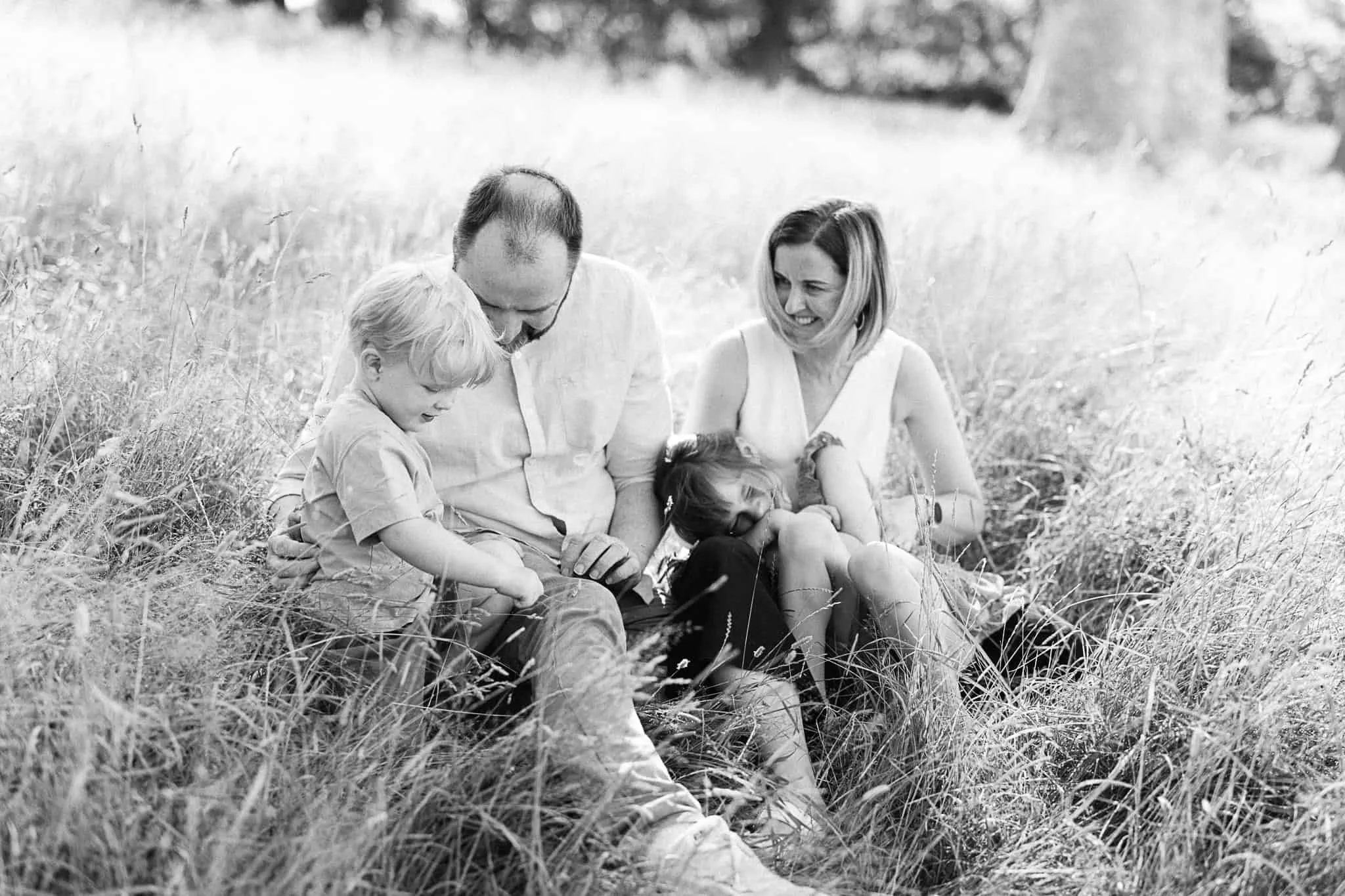Black and white photo of family in long grass during family photo session at Trelissick Gardens, Truro Cornwall
