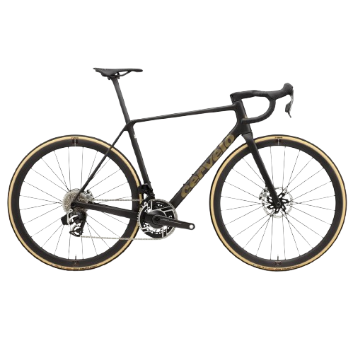 A black carbon fiber road bicycle with drop handlebars, thin tires, and disc brakes, leaning against a light-colored wall.