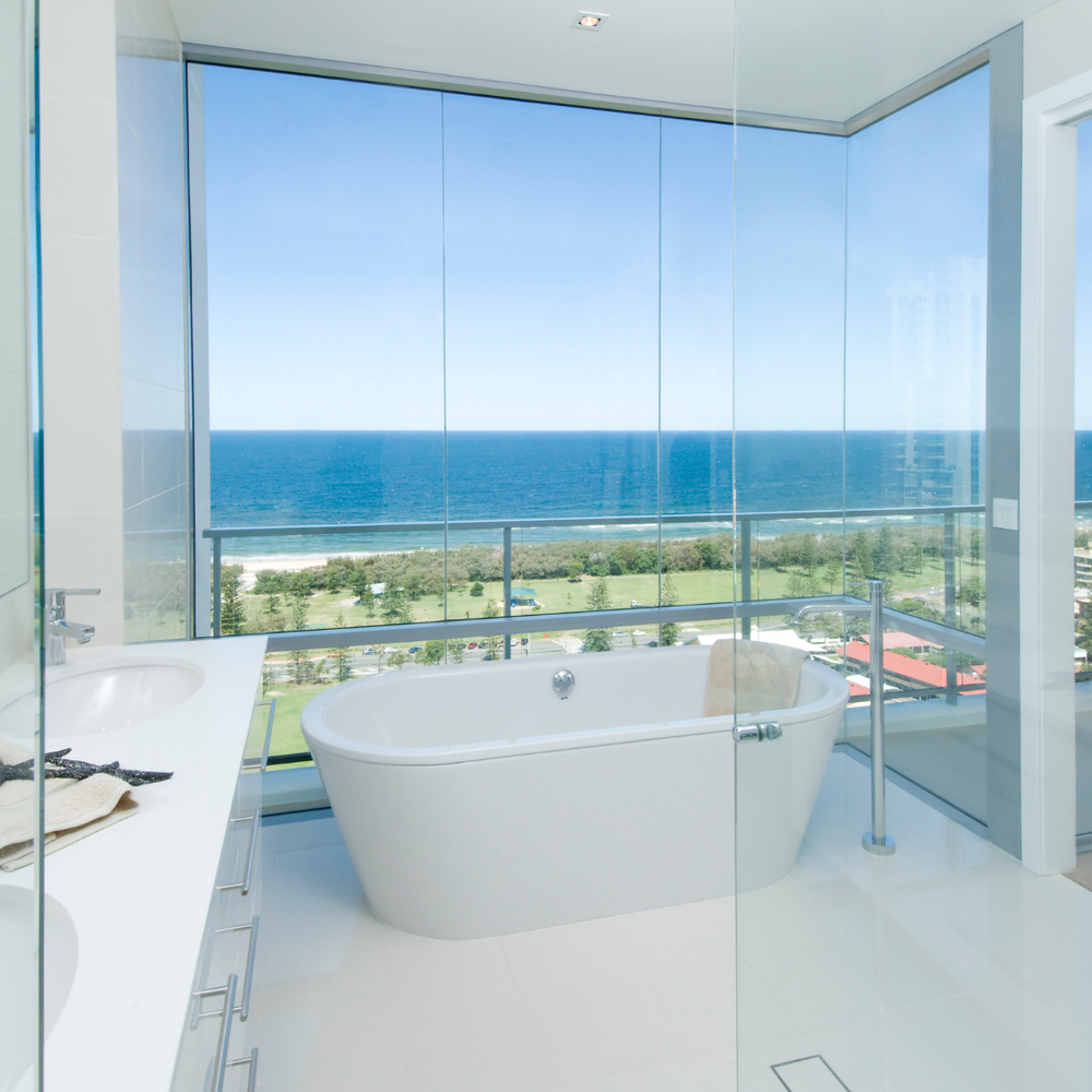 An all-white bathroom with a focus on a beautiful ocean view