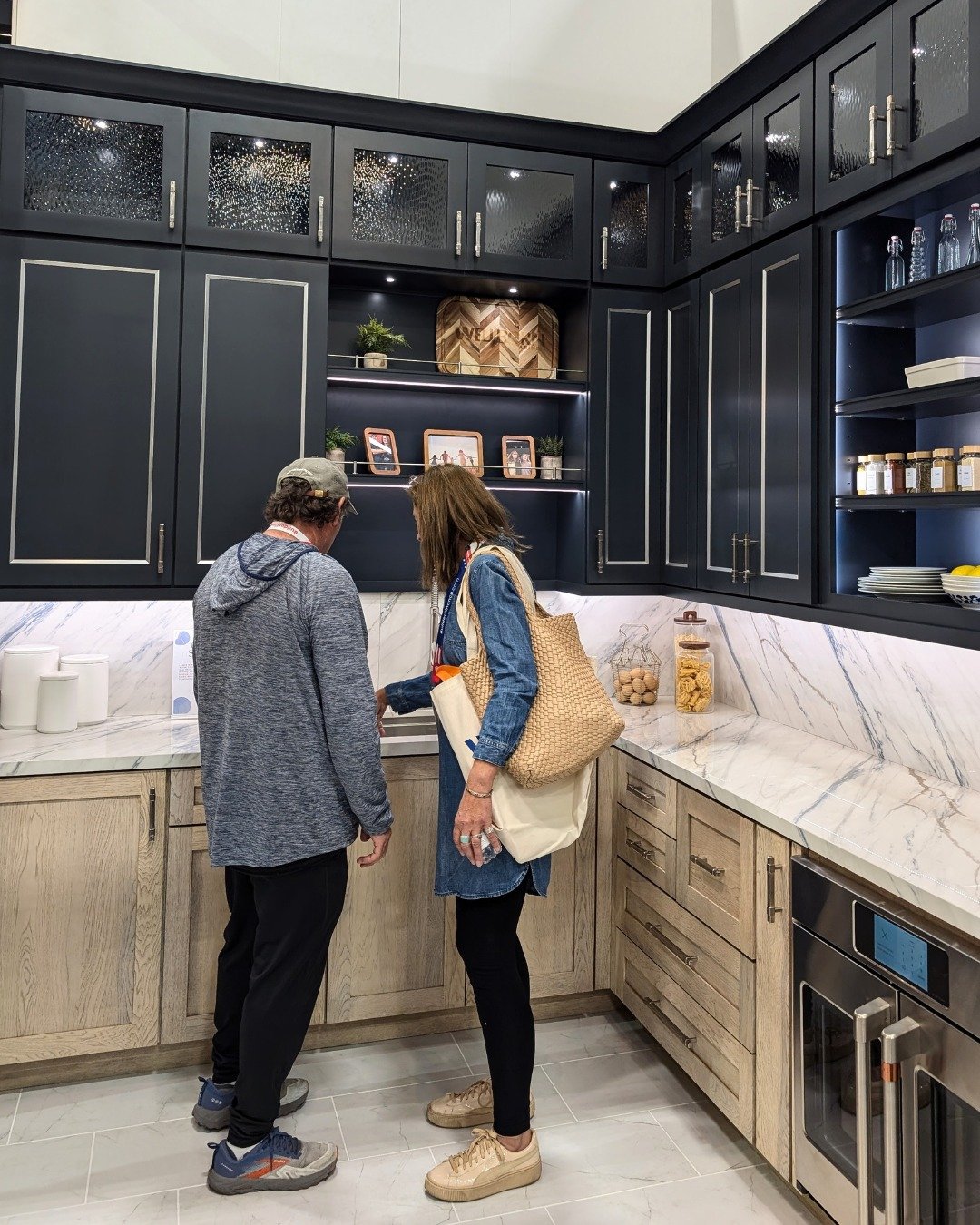 This corner scullery includes trending design features like two-toned cabinetry, a full slab backsplash, and a workstation sink.