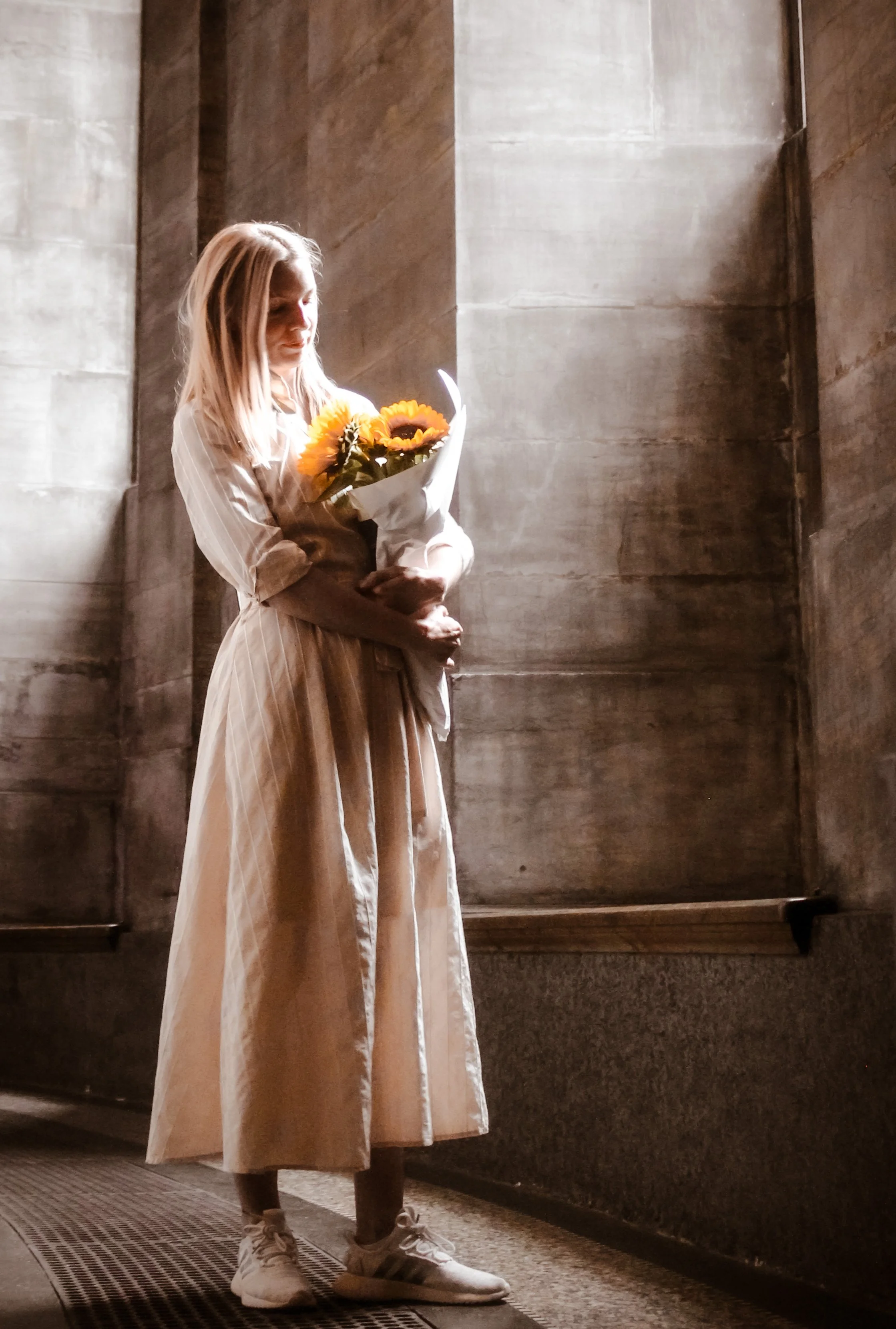 Kvinde holder en buket solsikker i en gryende solopgangs- eller aftendagsscene indendørs.