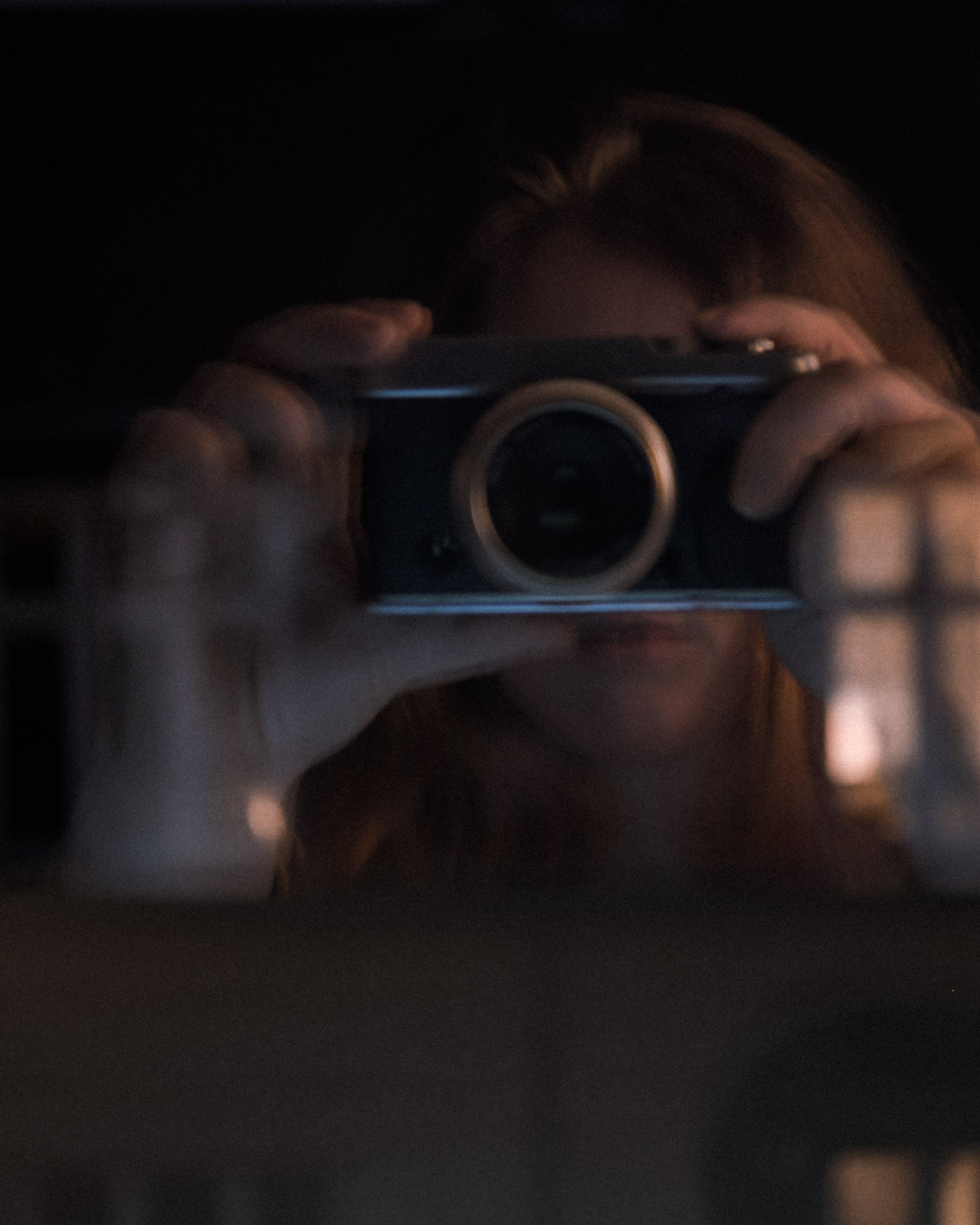 Person tager selfie med kamera i mørkt rum