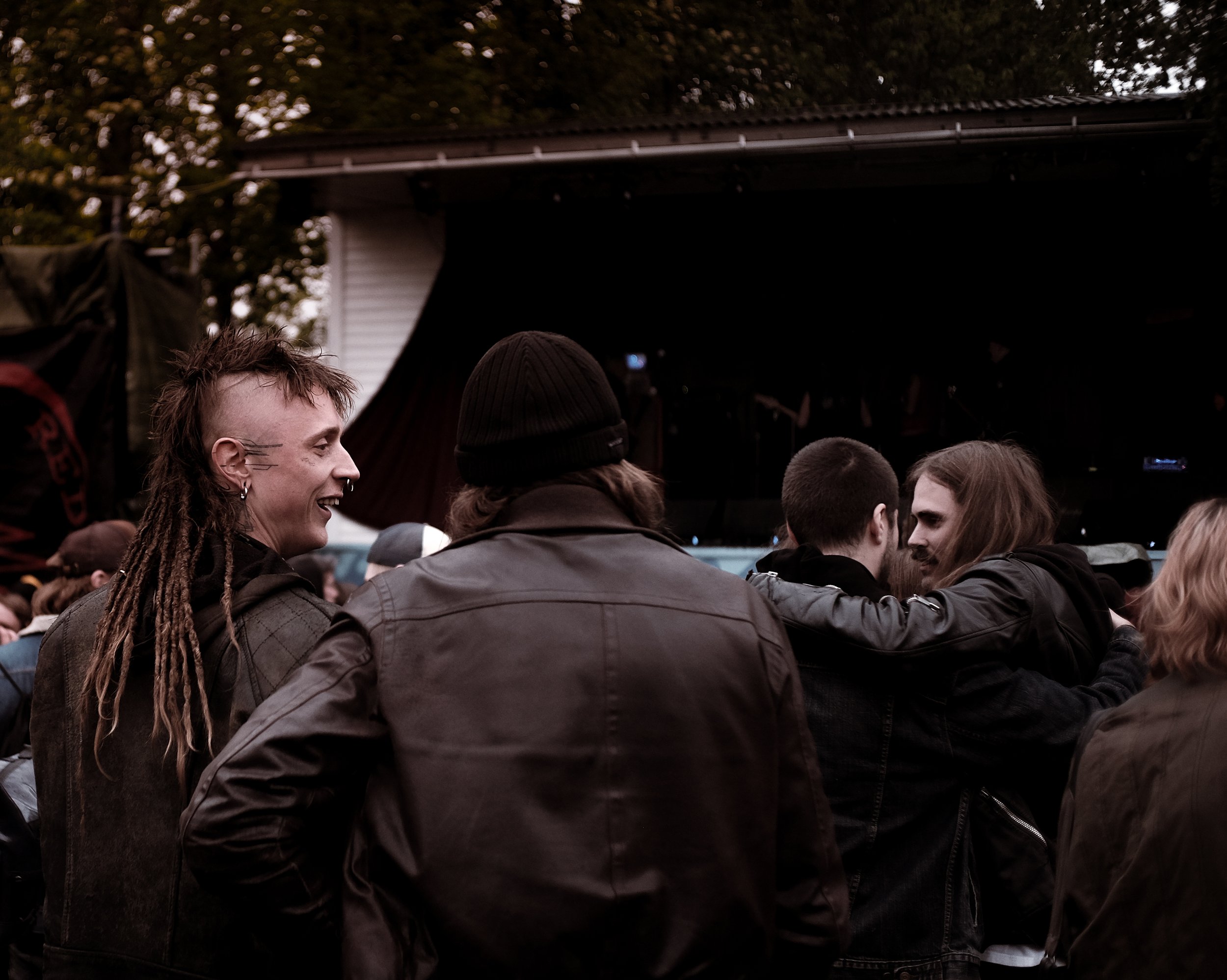 Gruppen af unge mennesker ved en udendørs koncert, nogle taler og hygger sig