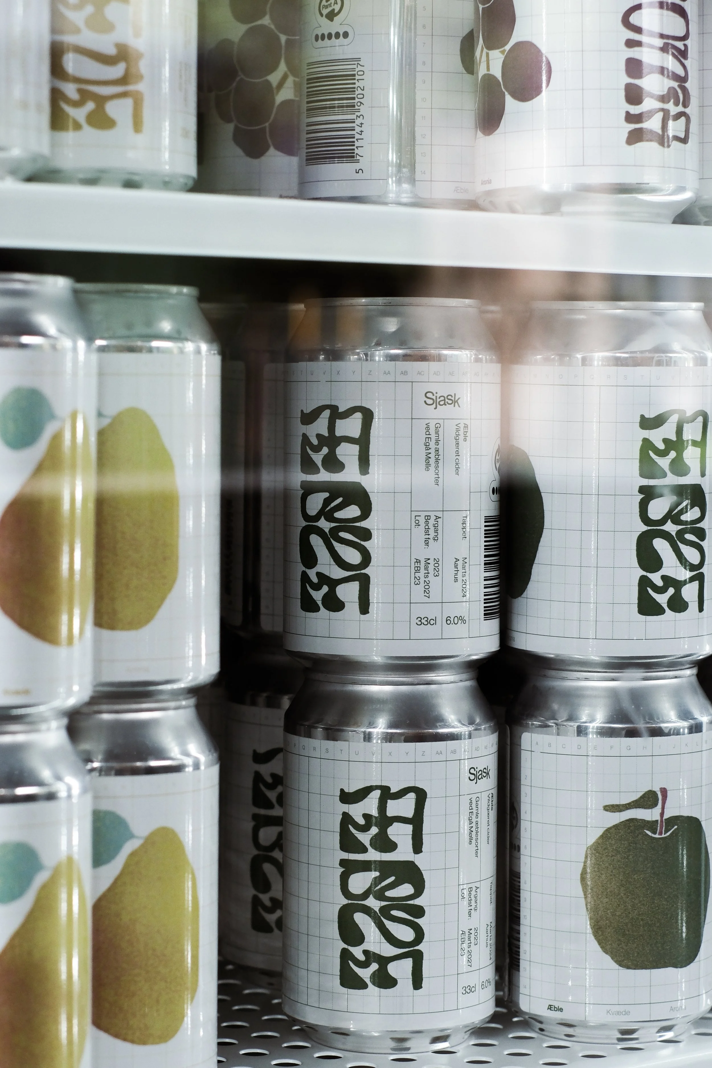 Cans with design resembling pears and apples on a store shelf.