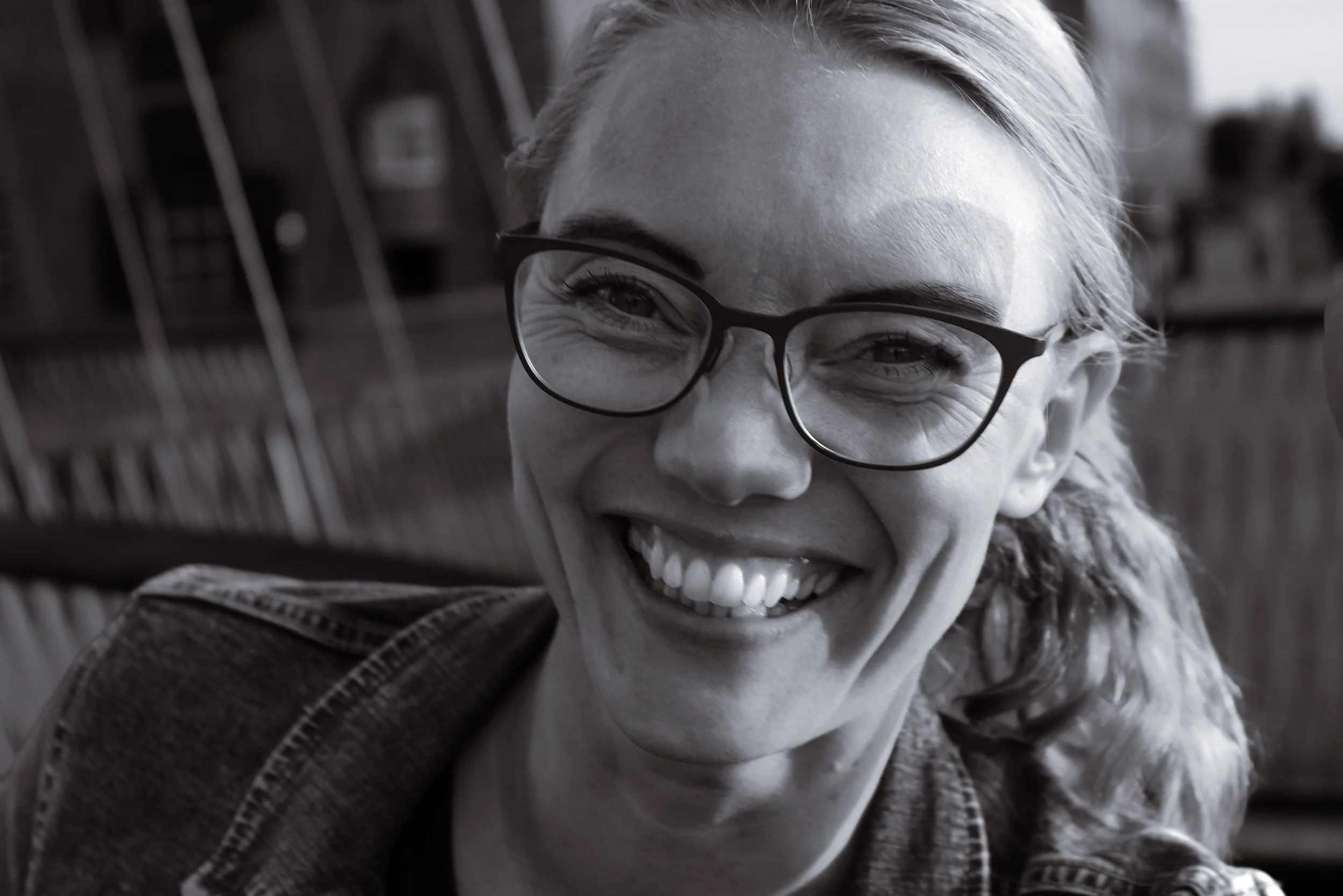 Et smilende kvindeperson, der har briller, i sort-hvid foto.