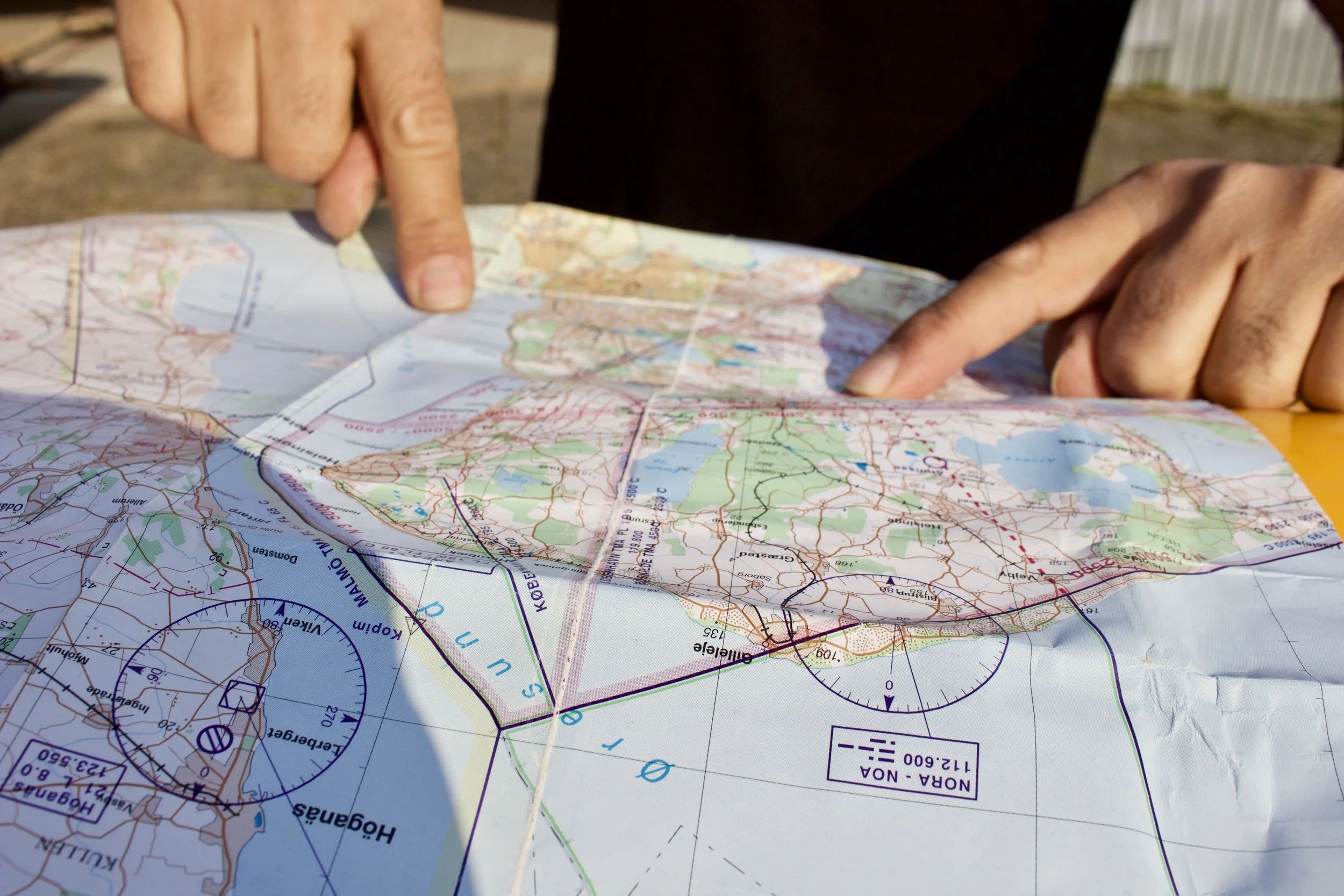 Personer der bruger fingrene til at pege på en topografisk kort.