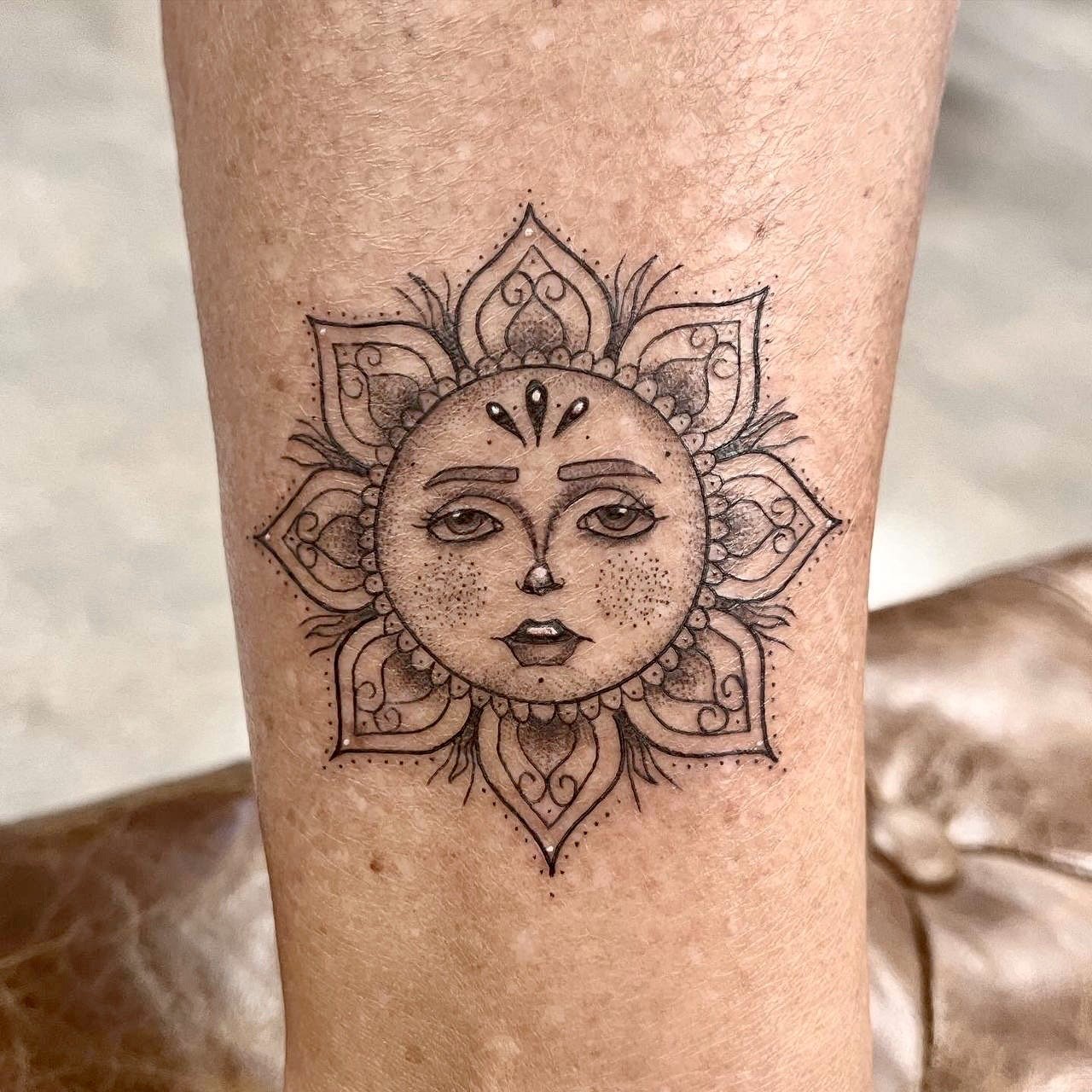  Dainty fineline tattoo of a sun. The rays are made of a simple mandala. Also the tattoo contains very light shading 