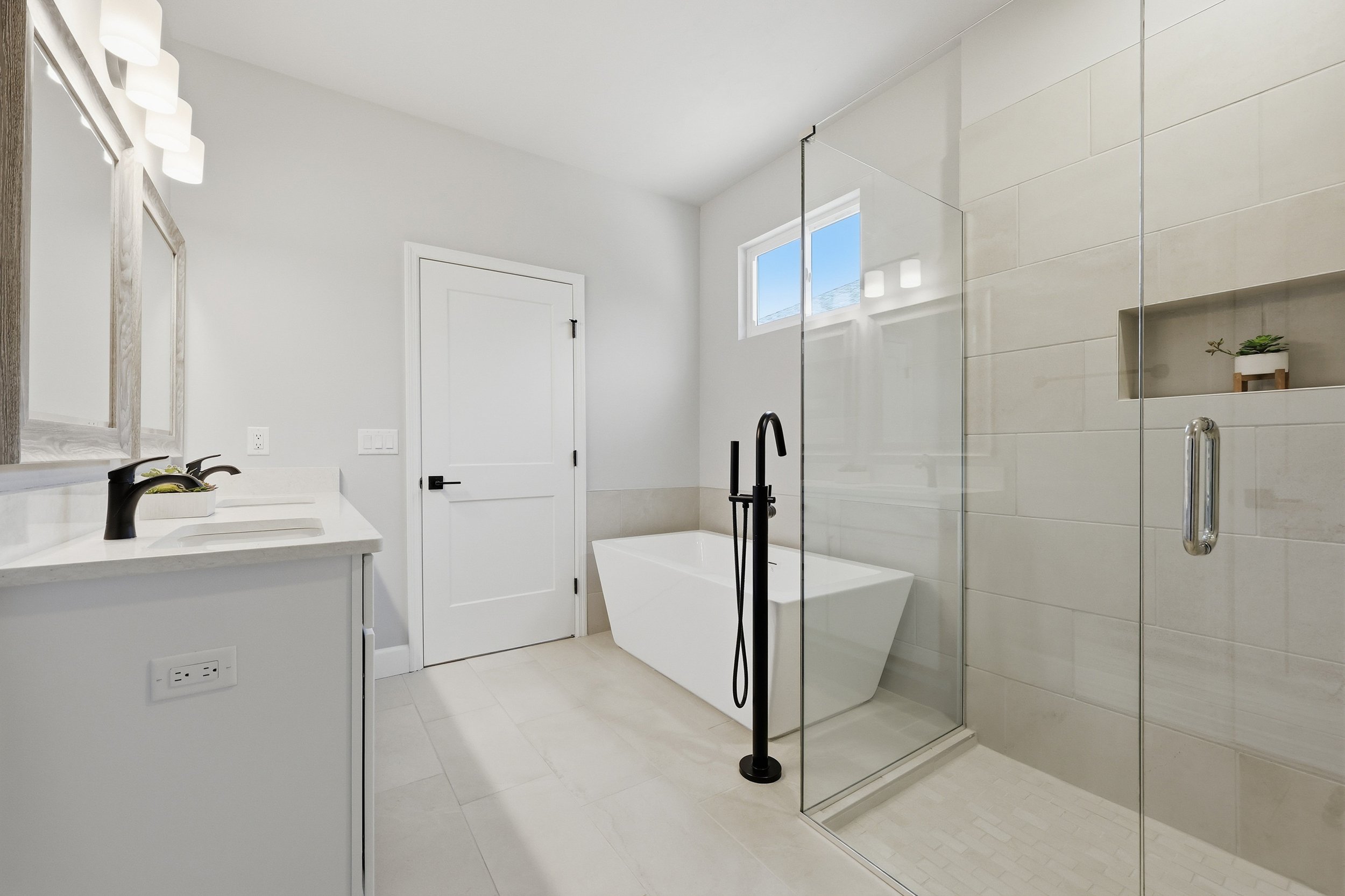 White, modern primary bathroom in the Milo model with double vanity, luxurious bathtub and walk in shower.