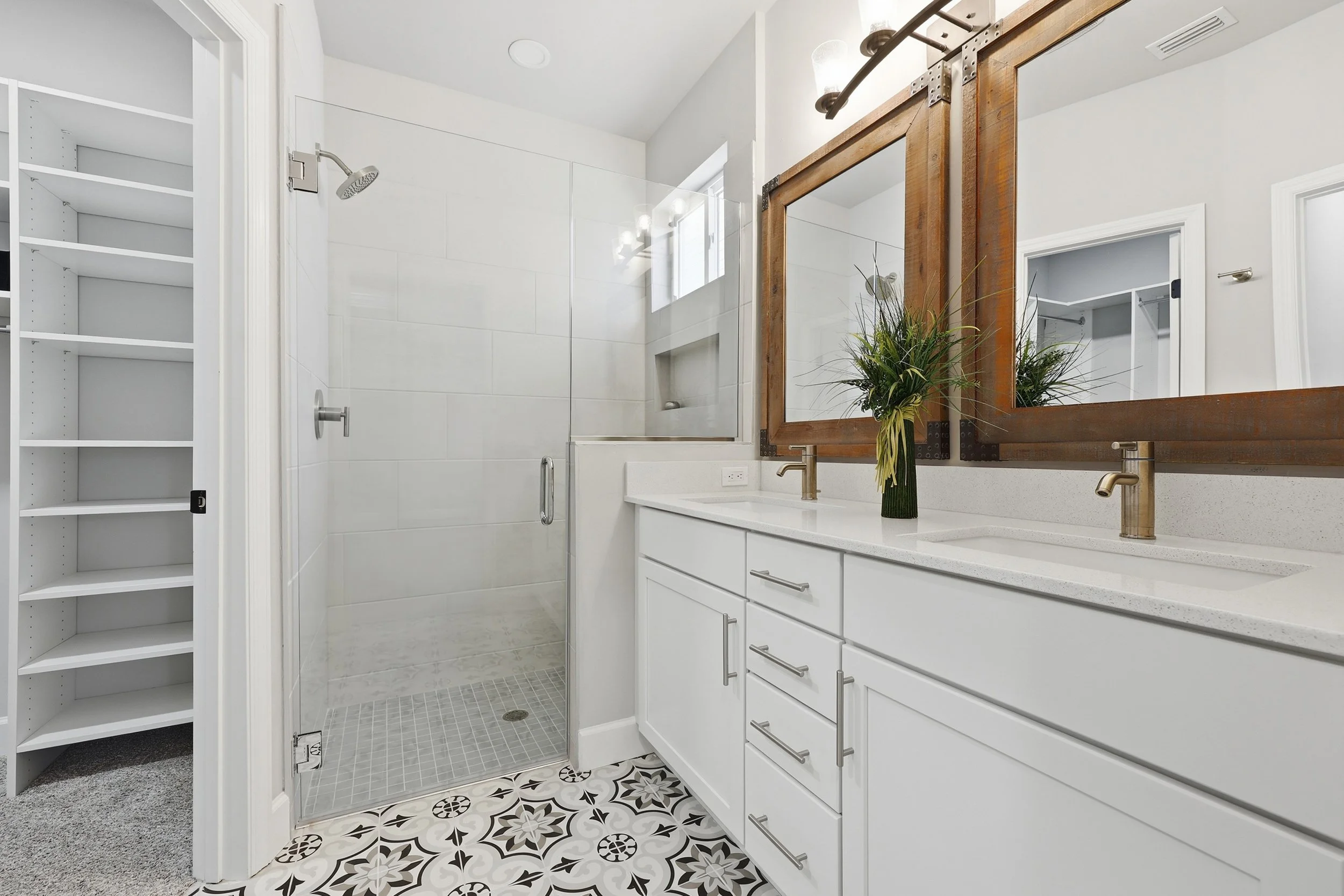 Primary bathroom in the Messina model with large walk-in closet, luxury shower with glass door, and a double vanity.