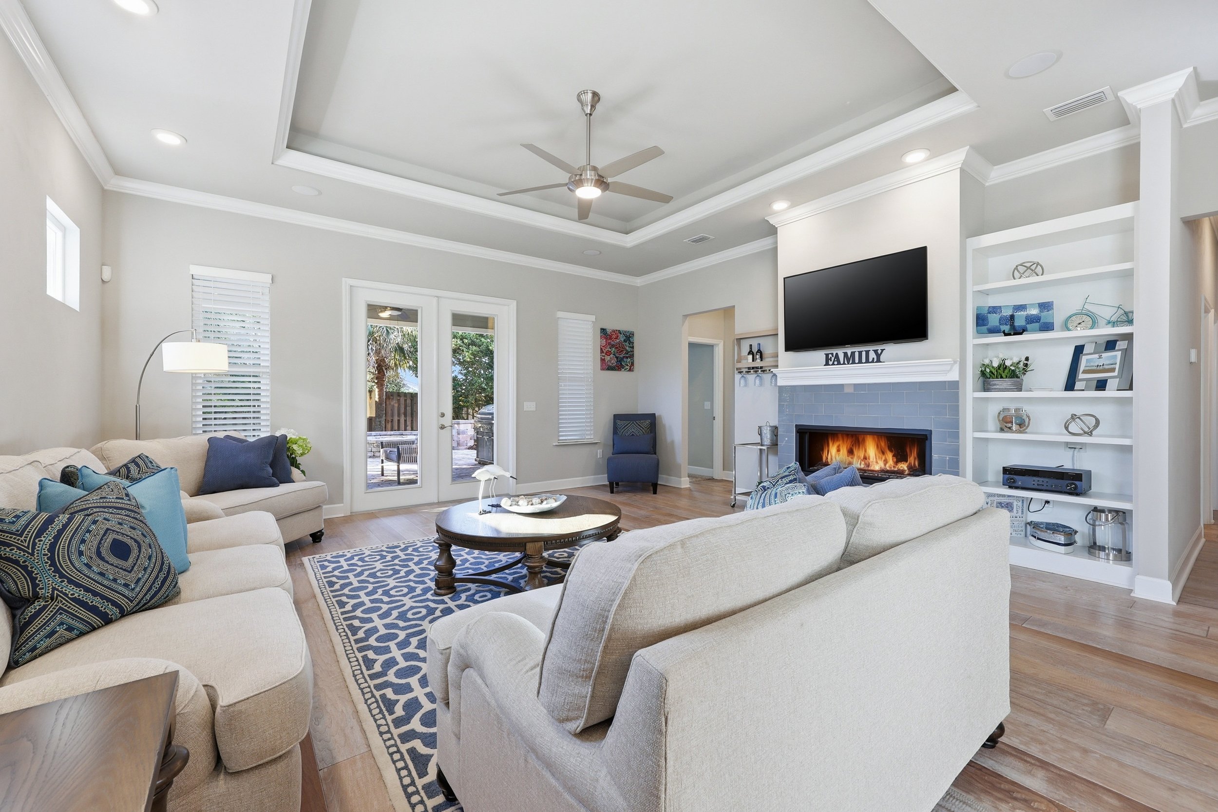 Open-plan living room with cozy seating, area rug, coffee table, twin windows, and neutral décor.