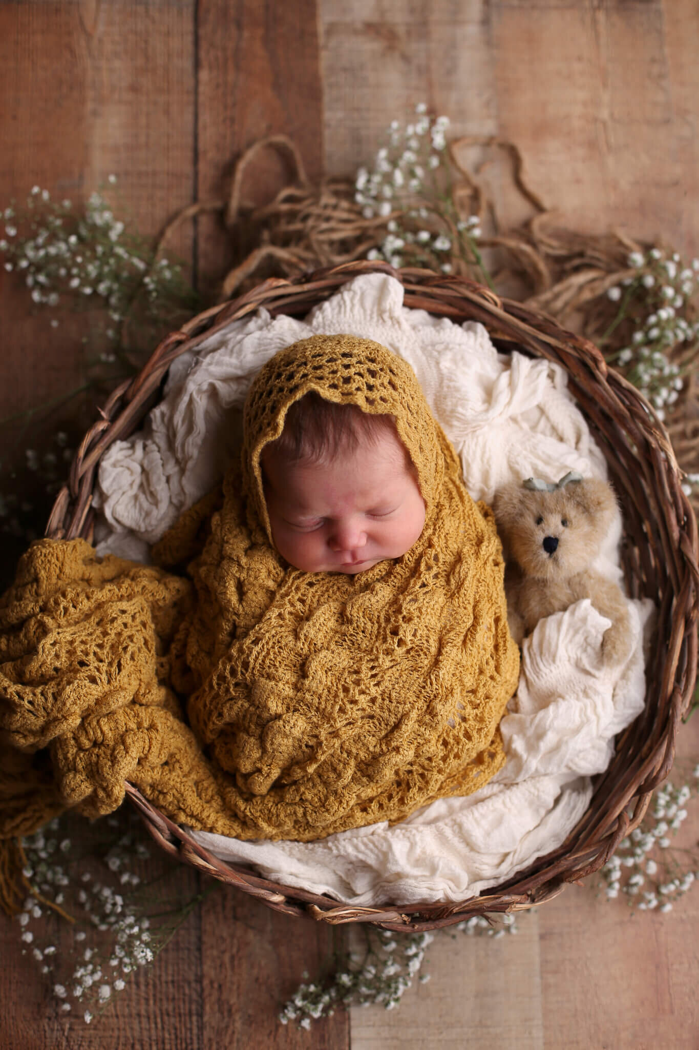  A picture of a newborn baby wrapped in a crocheted blanket, sleeping with a teddy bear in a basket surrounded by tiny flowers by Photography by L Rose - San Diego CA newborn photography 