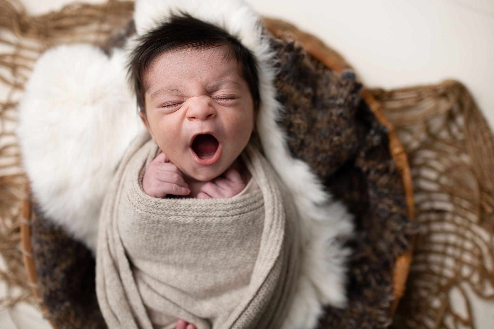  a big yawn by a newborn baby who is wrapped in a blanket 