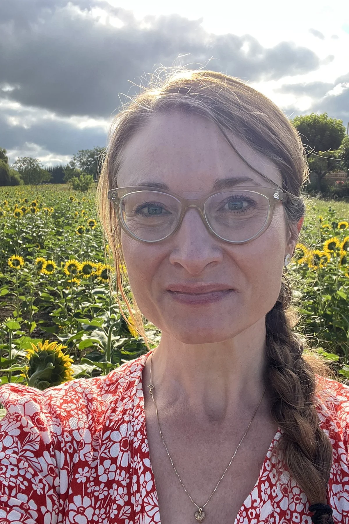 A headshot of Andrea in a field of sunflowers.