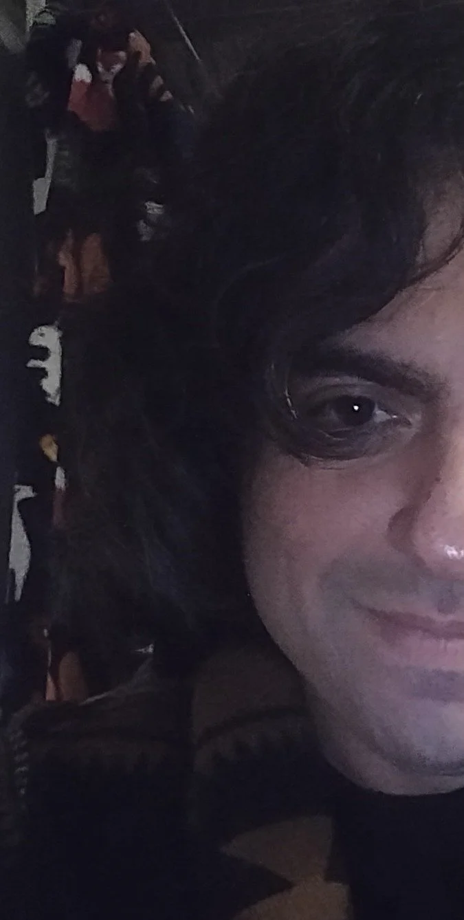 This is a photo of artist Robert Weissenberg. Half of his face is visible. He has dark hair and is smiling.