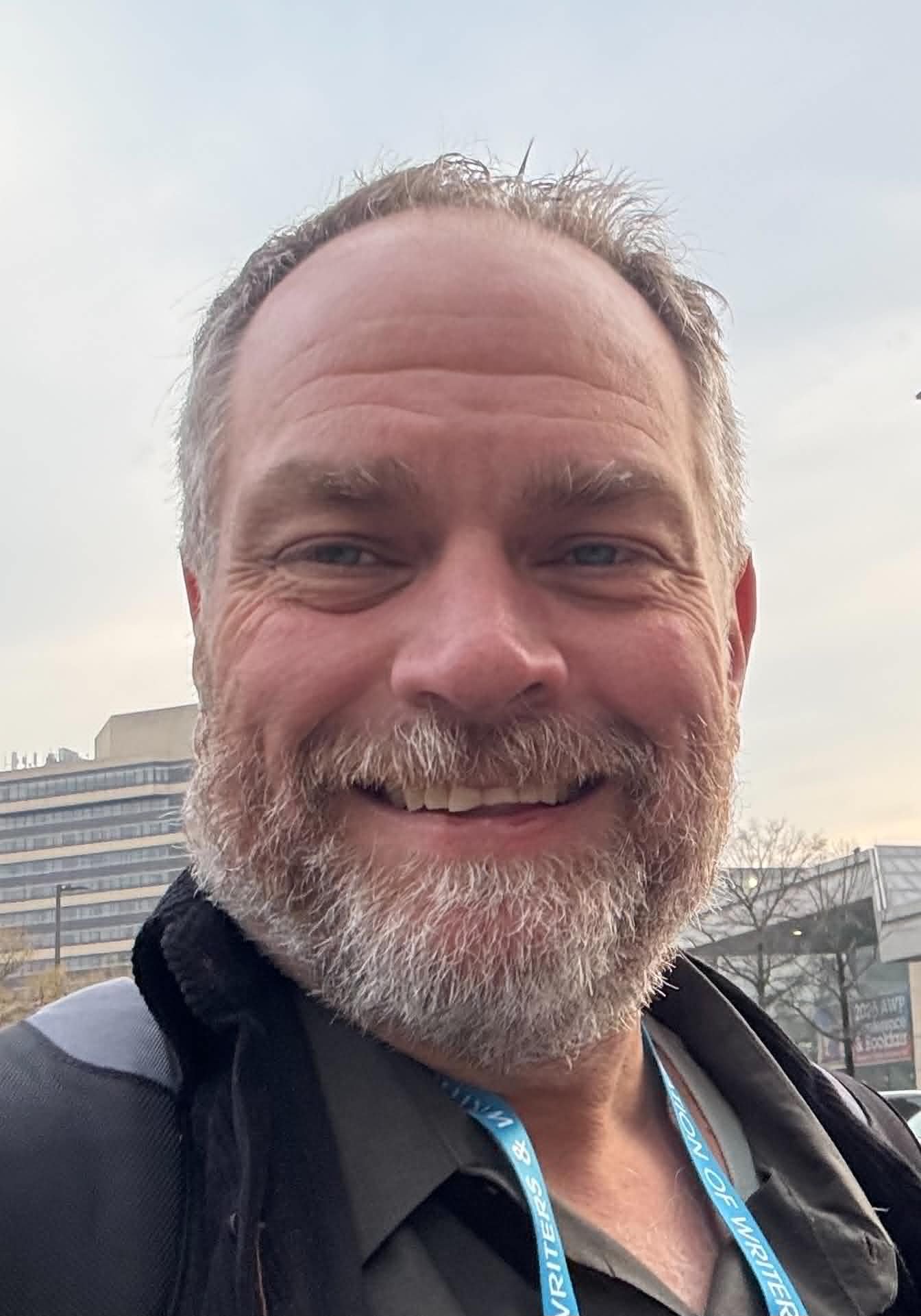 A headshot of Mike, a white man with a white beard, smiling.