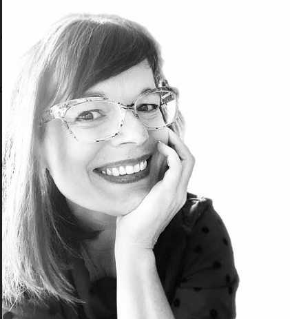 This is a picture of Sarah Quinn Rivara. She is resting her chin on her hand and smiling at the camera.