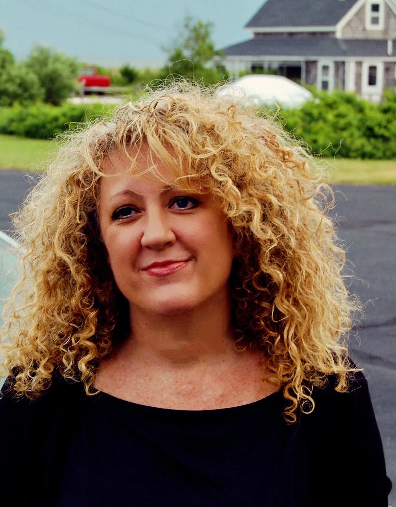 A headshot of Kelle, a woman with blonde curly hair.