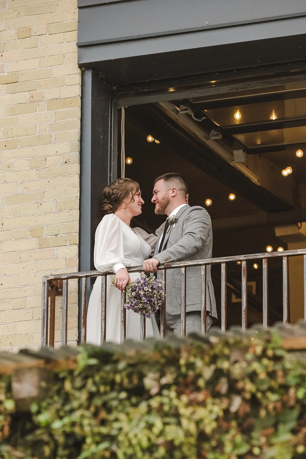 Bride and Groom Share Intimate Moment on Balcony with Purple Flowers Fedora Media Cambridge Ontario Four Fathers Brewery.jpg