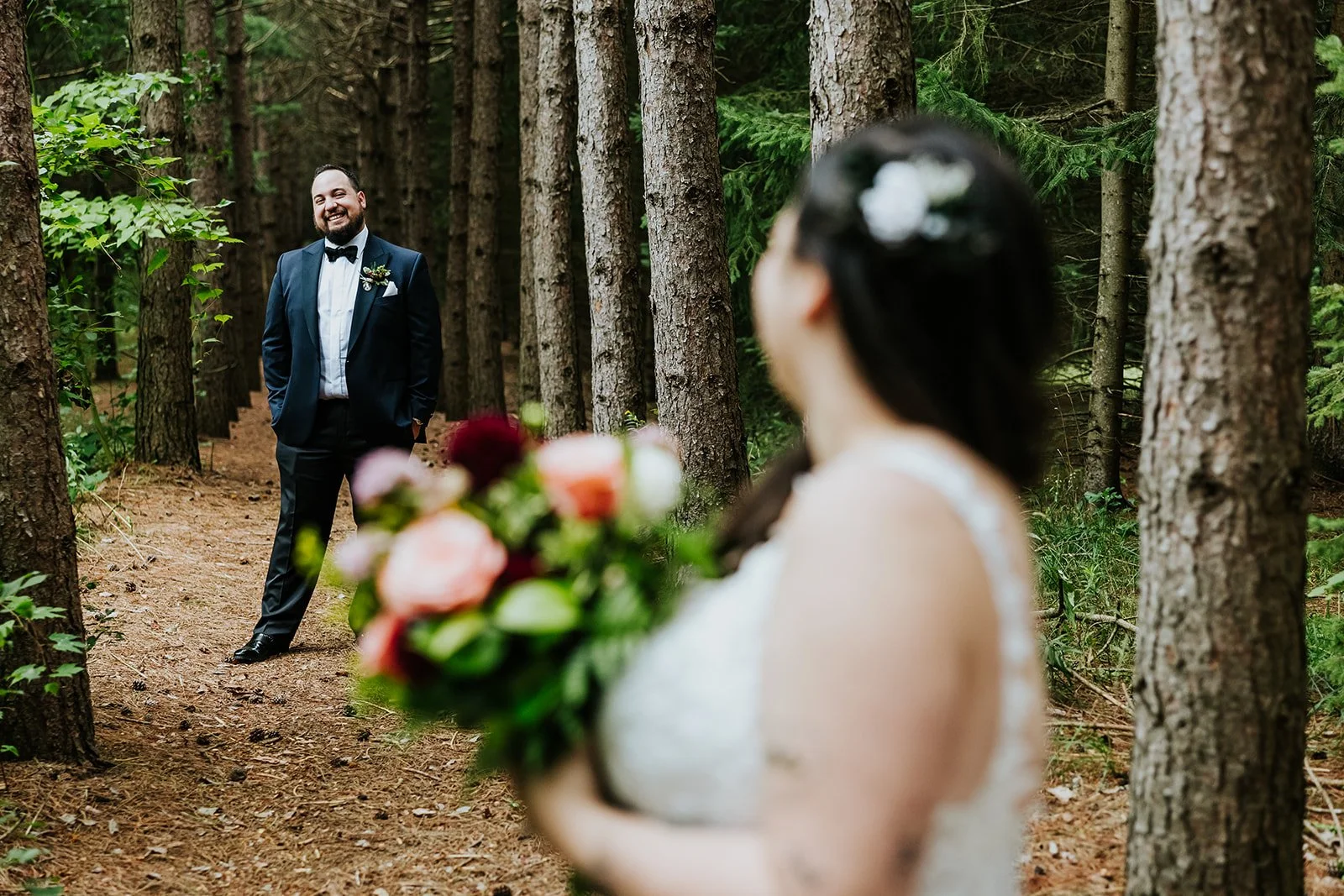 Groom in the woods with bride looking at him at Erin Estate photo by Fedora Media.jpg