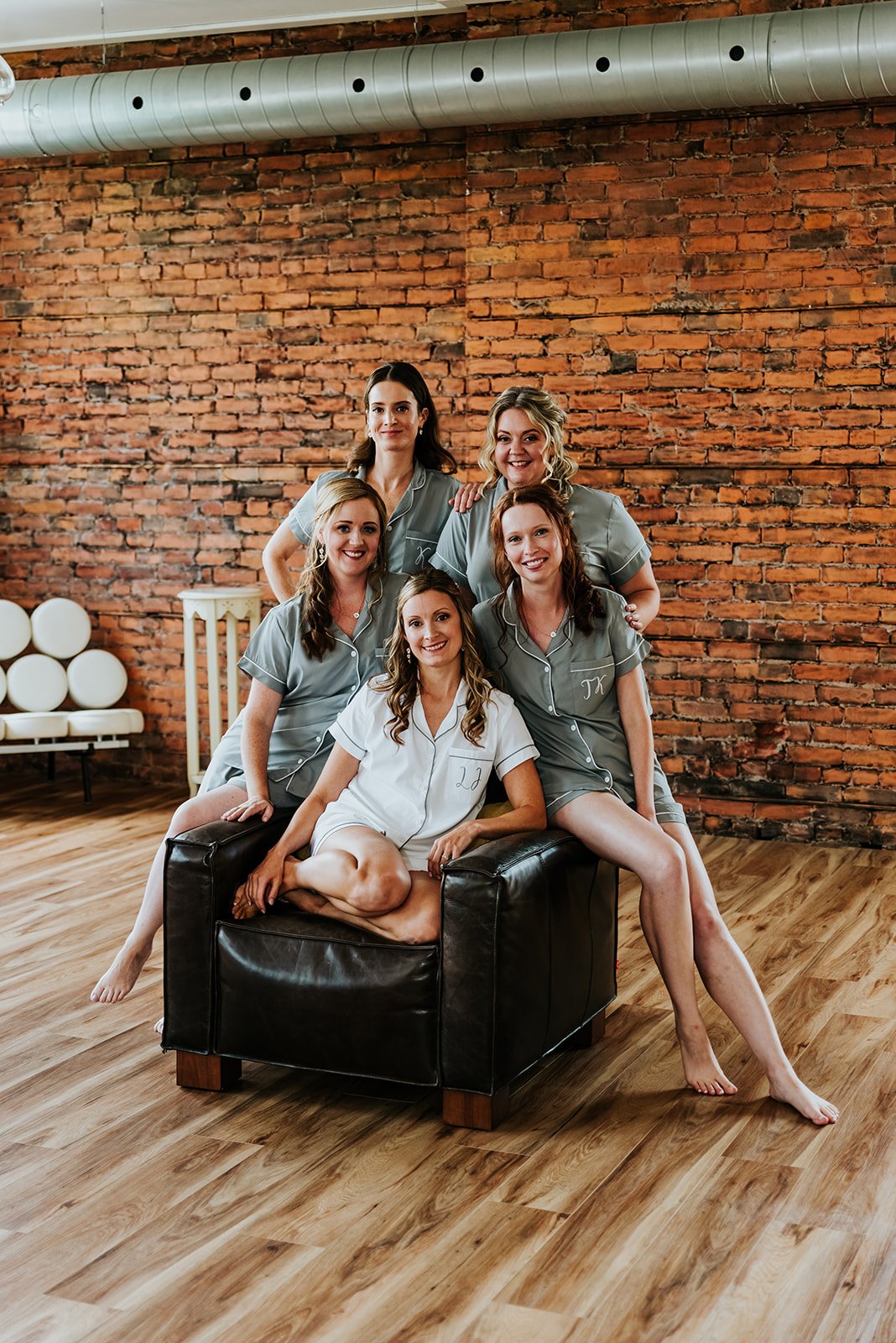 Bride poses with bridesmaids in pyjamas in front of brick wall photo by Fedora Media.jpg